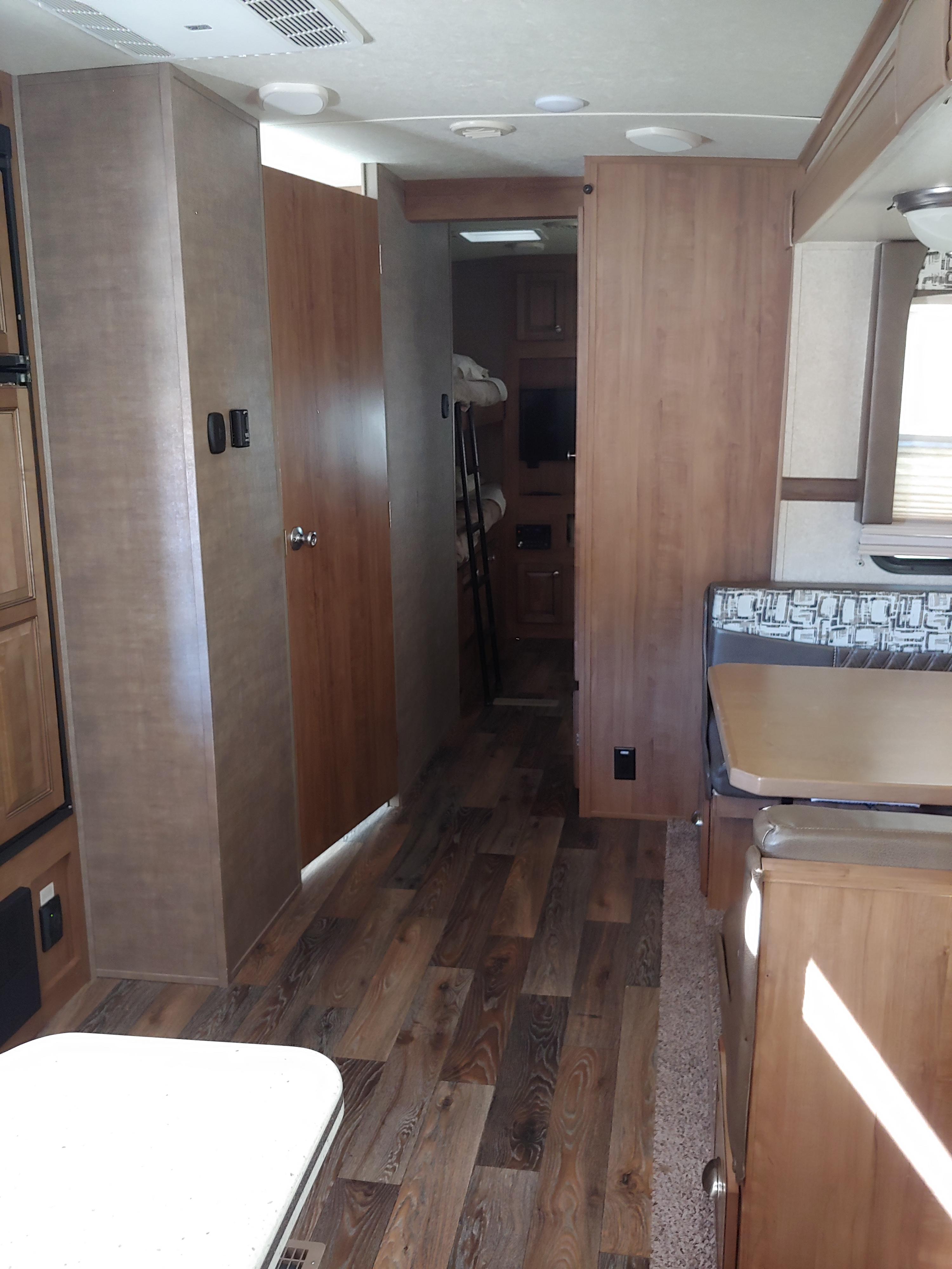 RV rental interior with wood floor, dinette, and bunk beds visible down the hallway.. Forest River Rockwood Signature Ultra Lite 2017