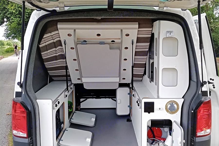 RV rental: Inside a neat camper van conversion, showing a raised bed setup and multiple storage compartments.. Volkswagen Transporter T6.1 2022