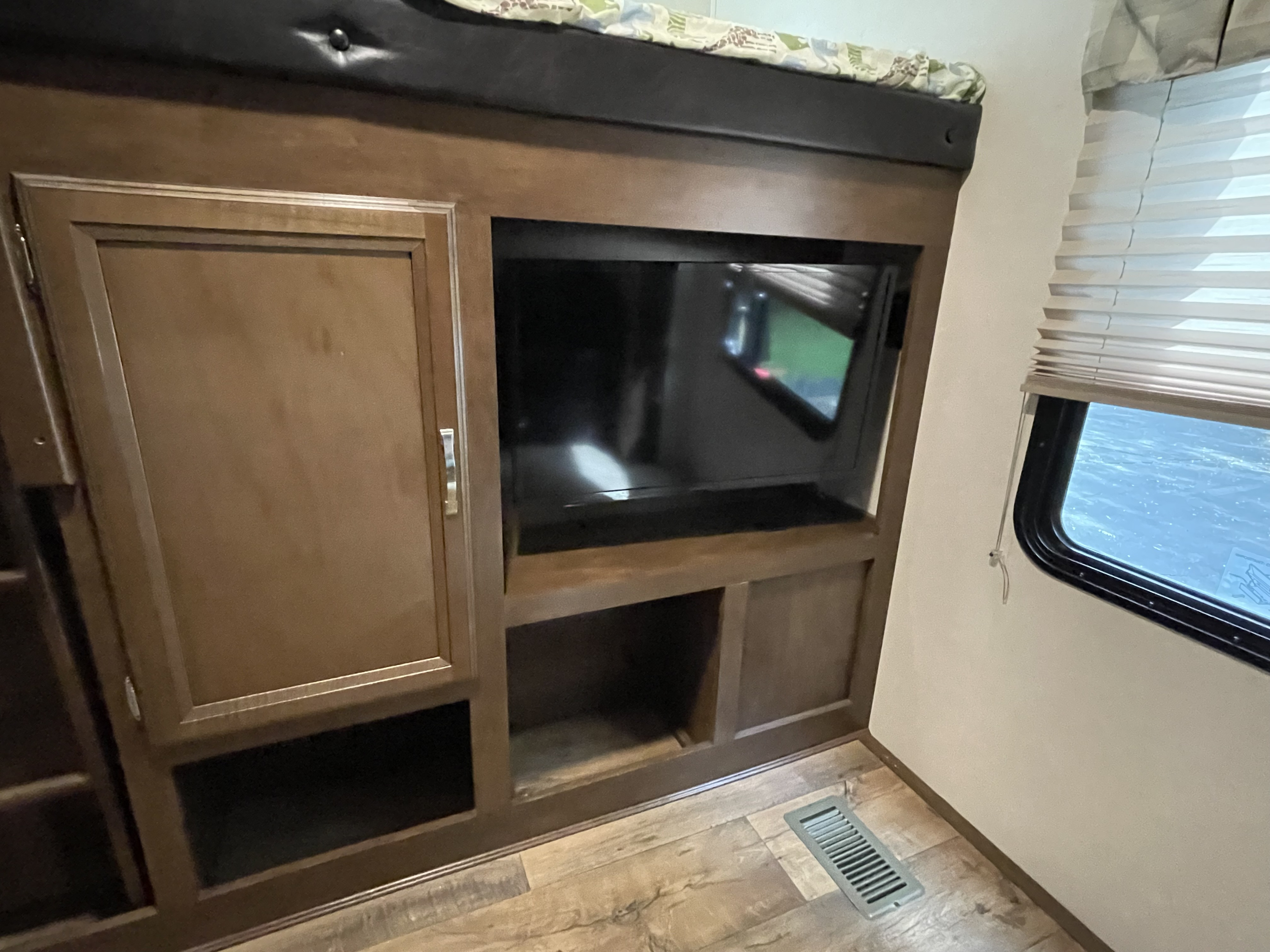 RV rental interior showcases a cozy bunk bed, built-in TV, storage cabinetry, and a window with blinds.. Forest River Wildwood Heritage Glen Lite 2018