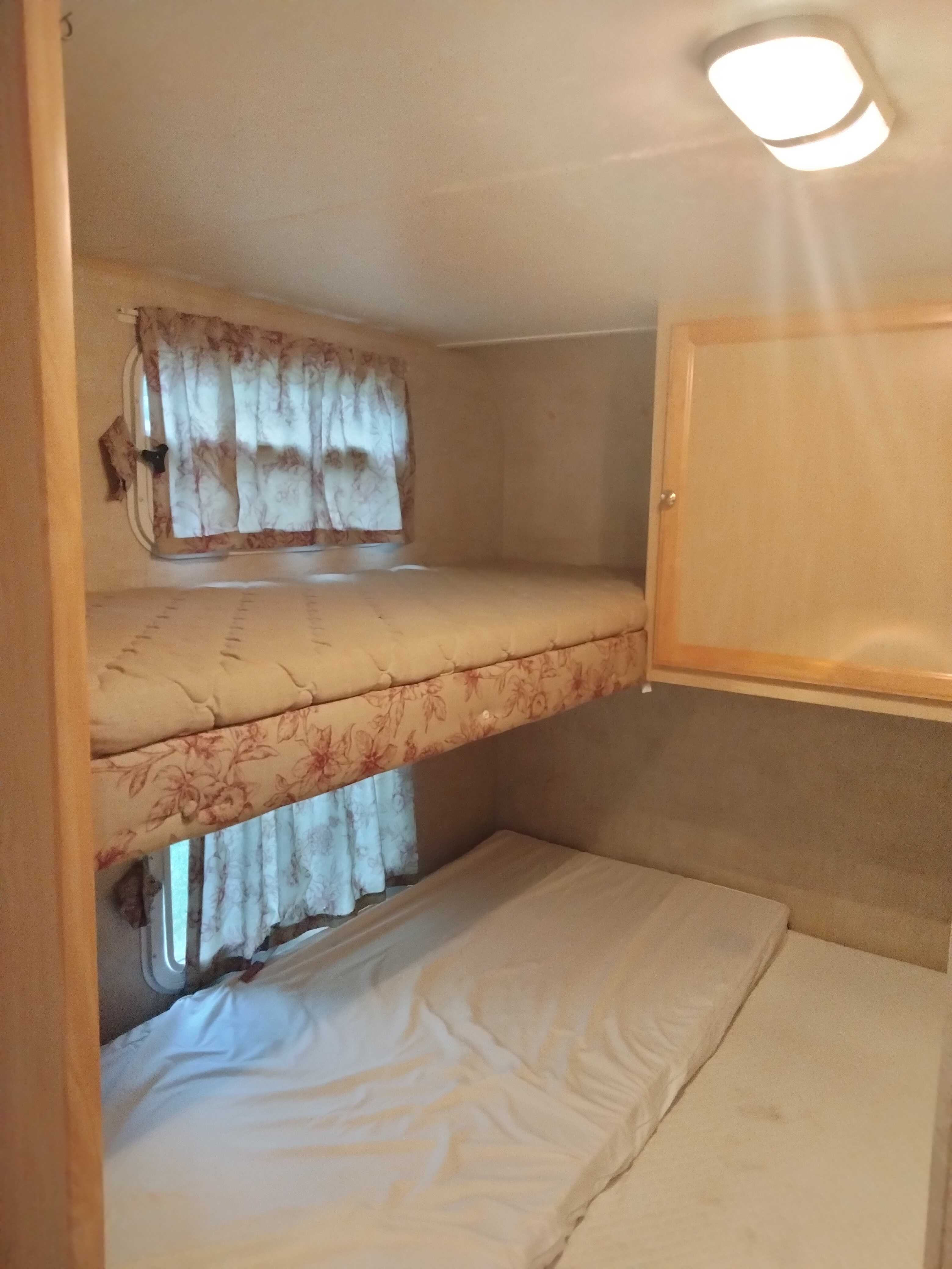 RV rental interior with stacked bunk beds, windows, and a ceiling light for a compact sleeping area.. Jayco Jay Feather 29M 2005