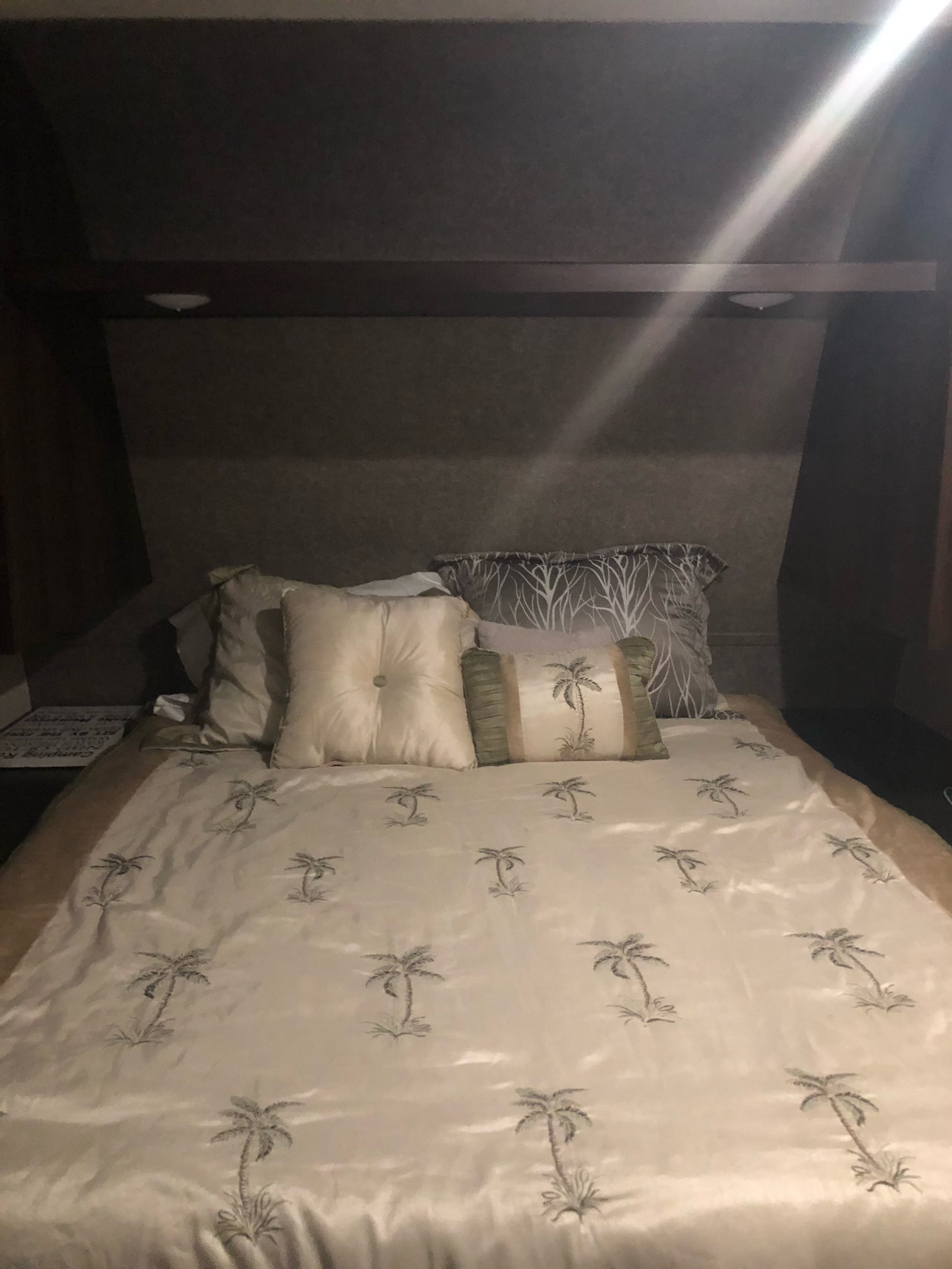 Inside an RV rental: a neatly made bedroom featuring palm tree bedding and pillows, offering cozy comfort for travelers.. Jayco Jay Flight 2020