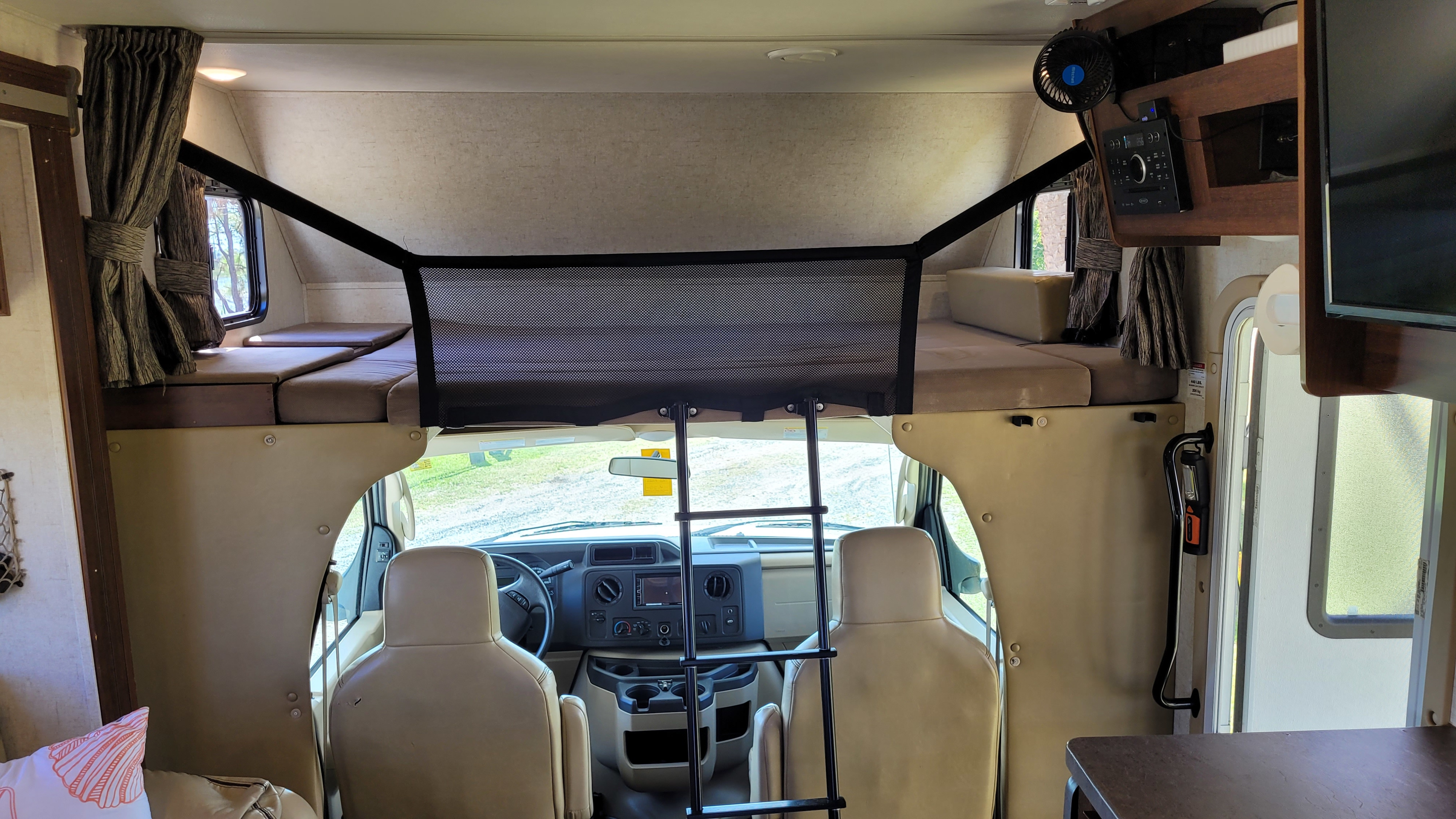 Spacious RV rental interior showing over-cab bunk bed, driver's cab, and amenities. Perfect for family adventures.. Forest River Sunseeker 2018