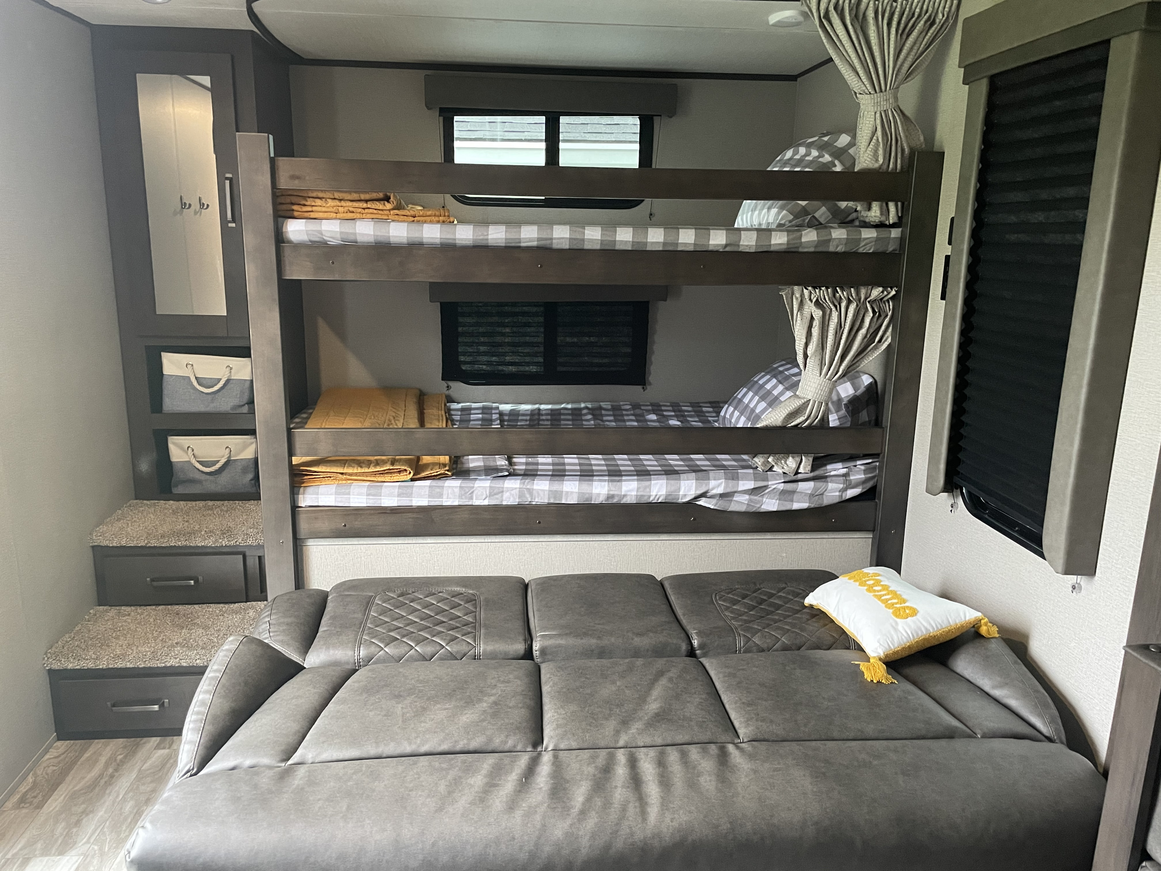 RV rental interior features bunk beds with plaid bedding, comfortable sofa, and built-in stair storage, all in gray and white tones.. Grand Design Transcend 265bh 2021