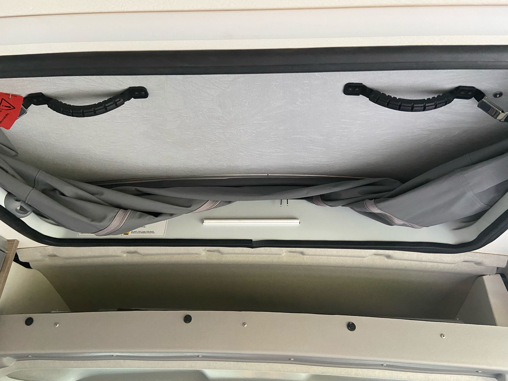 Overhead view in an RV rental reveals a pop-top ceiling with handles, lighting, and accessible storage cubbies.. Winnebago Solis 2021