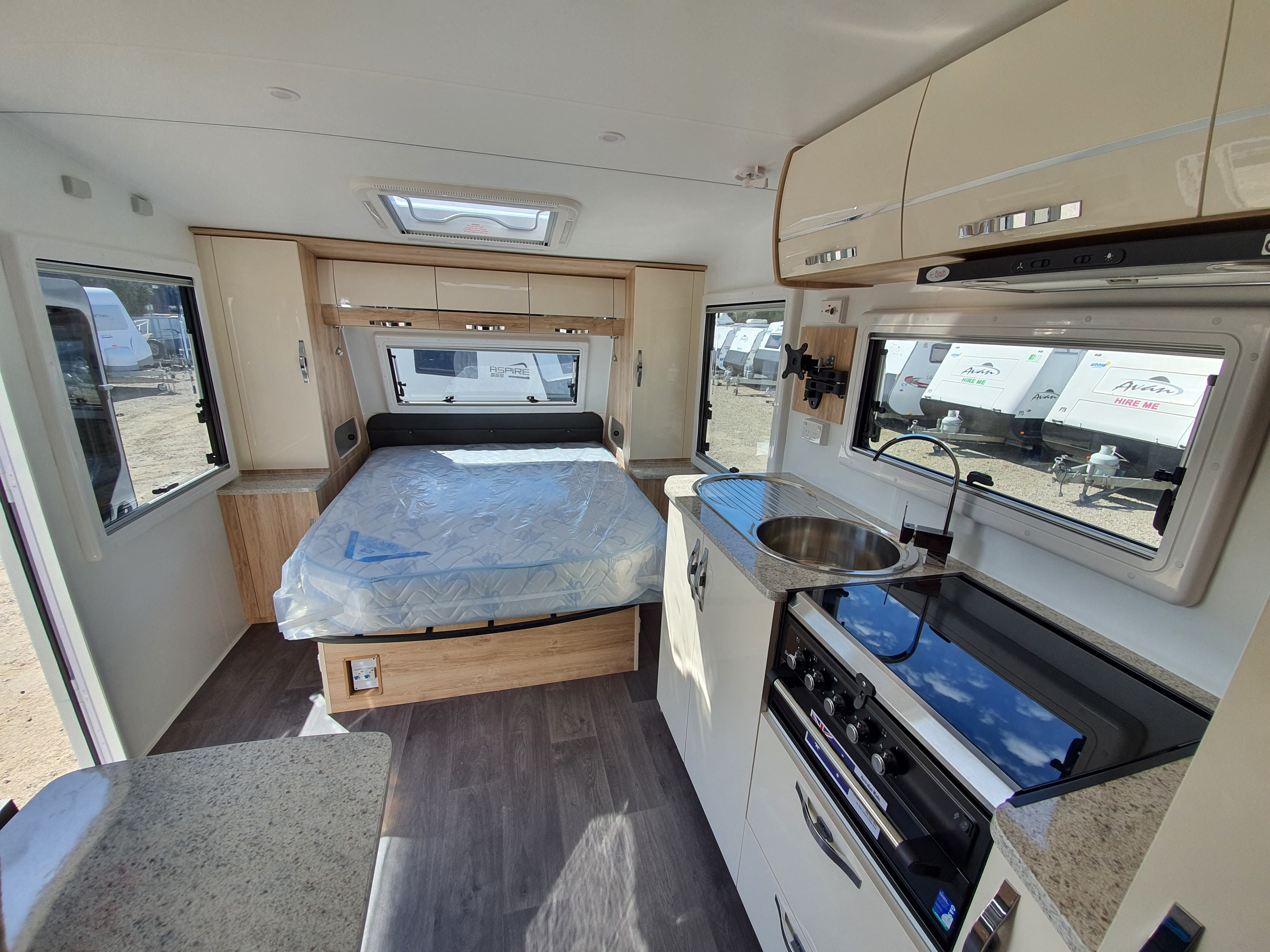Spacious rv rental interior featuring a comfy bed, modern kitchenette, & large windows overlooking other caravans.. Avan Aspire 617 Family 2021