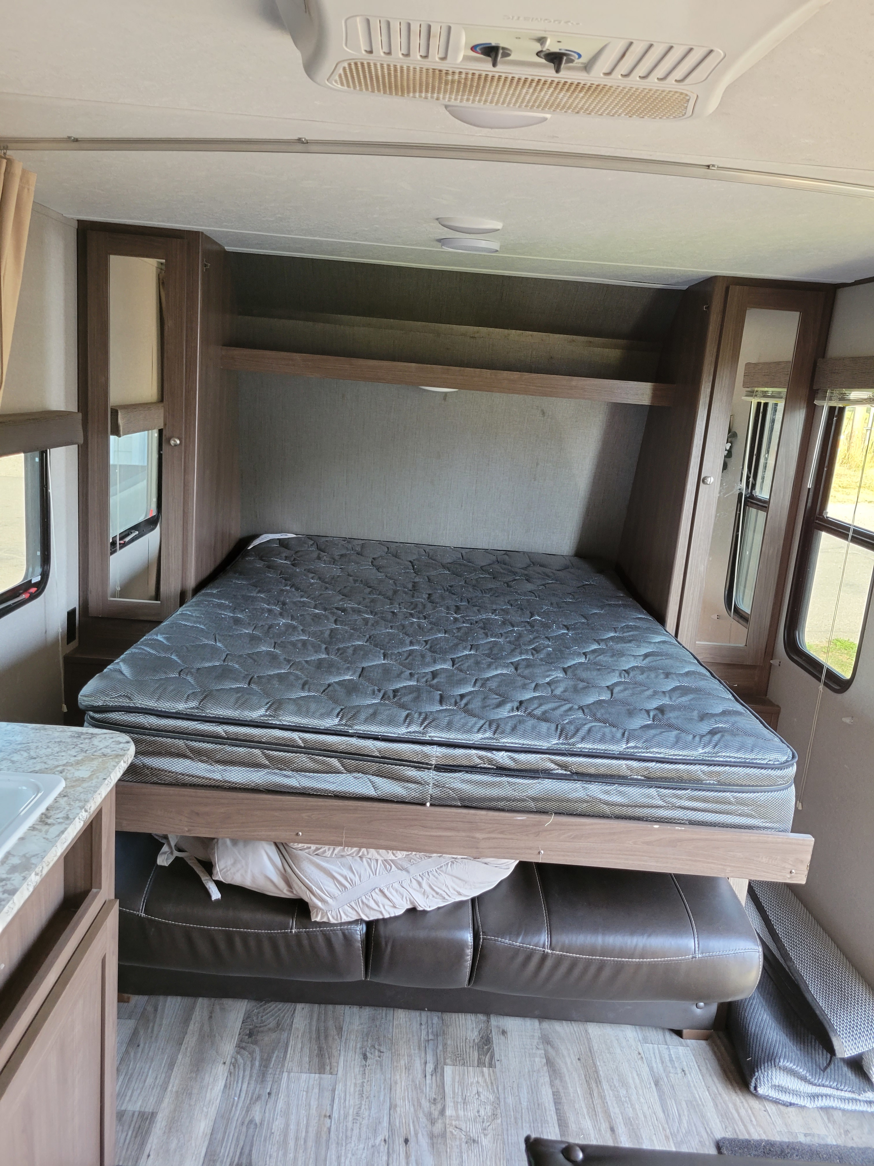 RV rental: Cozy bedroom with an elevated mattress over a convertible sofa, overhead storage, & windows.. Keystone Hideout 2019