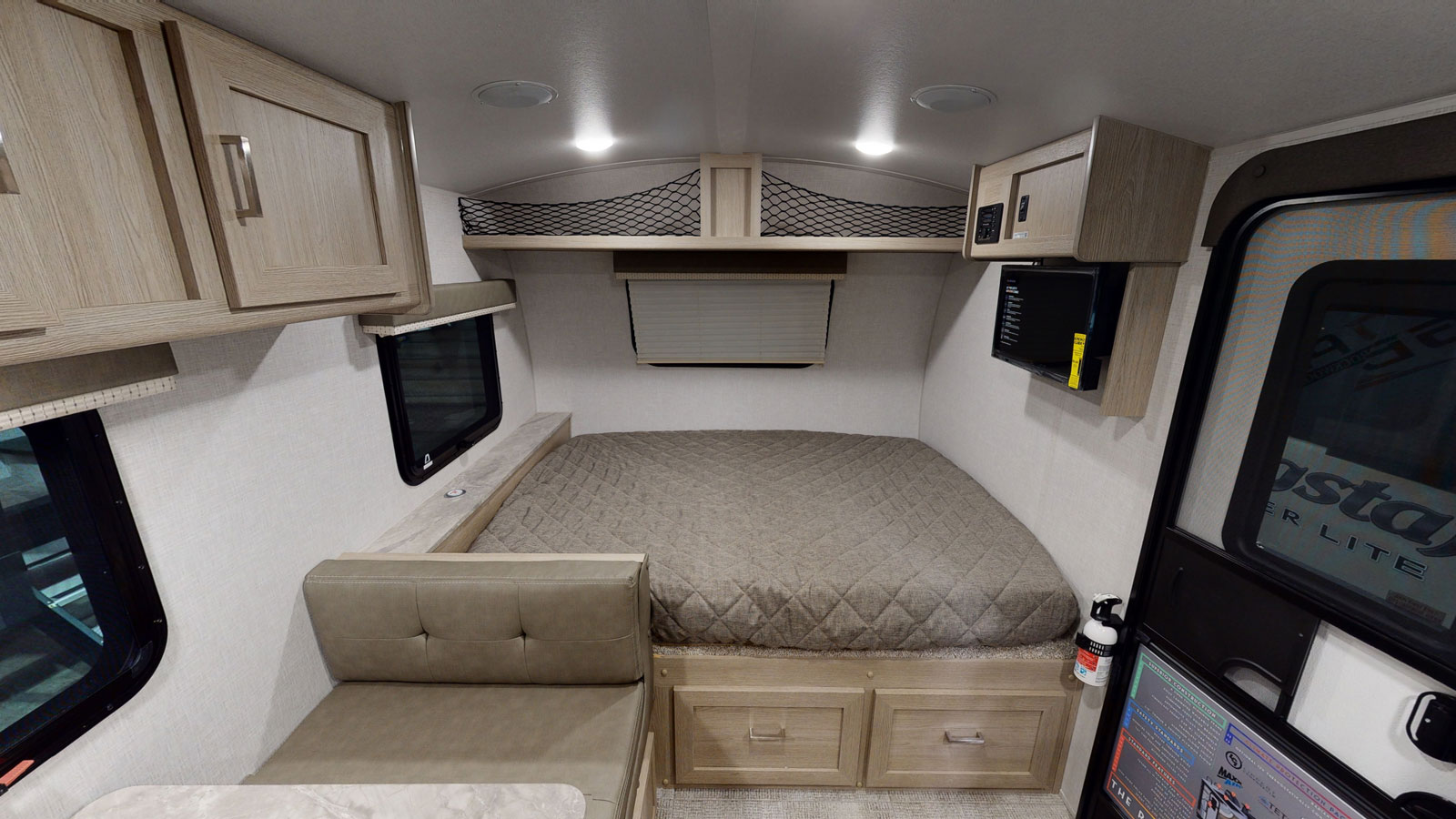Compact RV rental interior featuring a cozy bed, small dinette, overhead storage, and microwave.. Forest River Other 2021