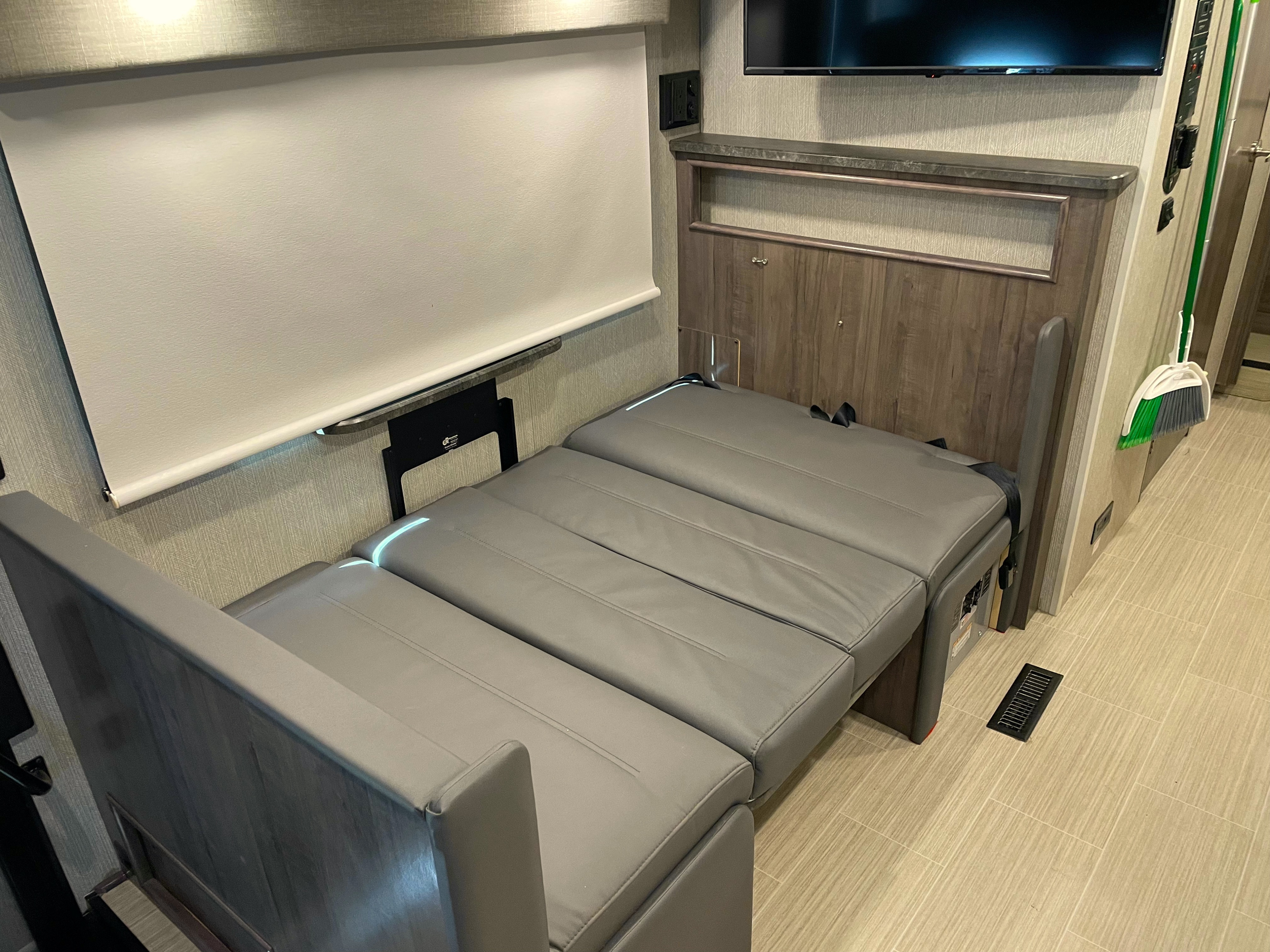 Experience comfort in this RV rental with a gray convertible bed/dinette, roller shade, and wall-mounted TV.. Winnebago Adventurer 2022