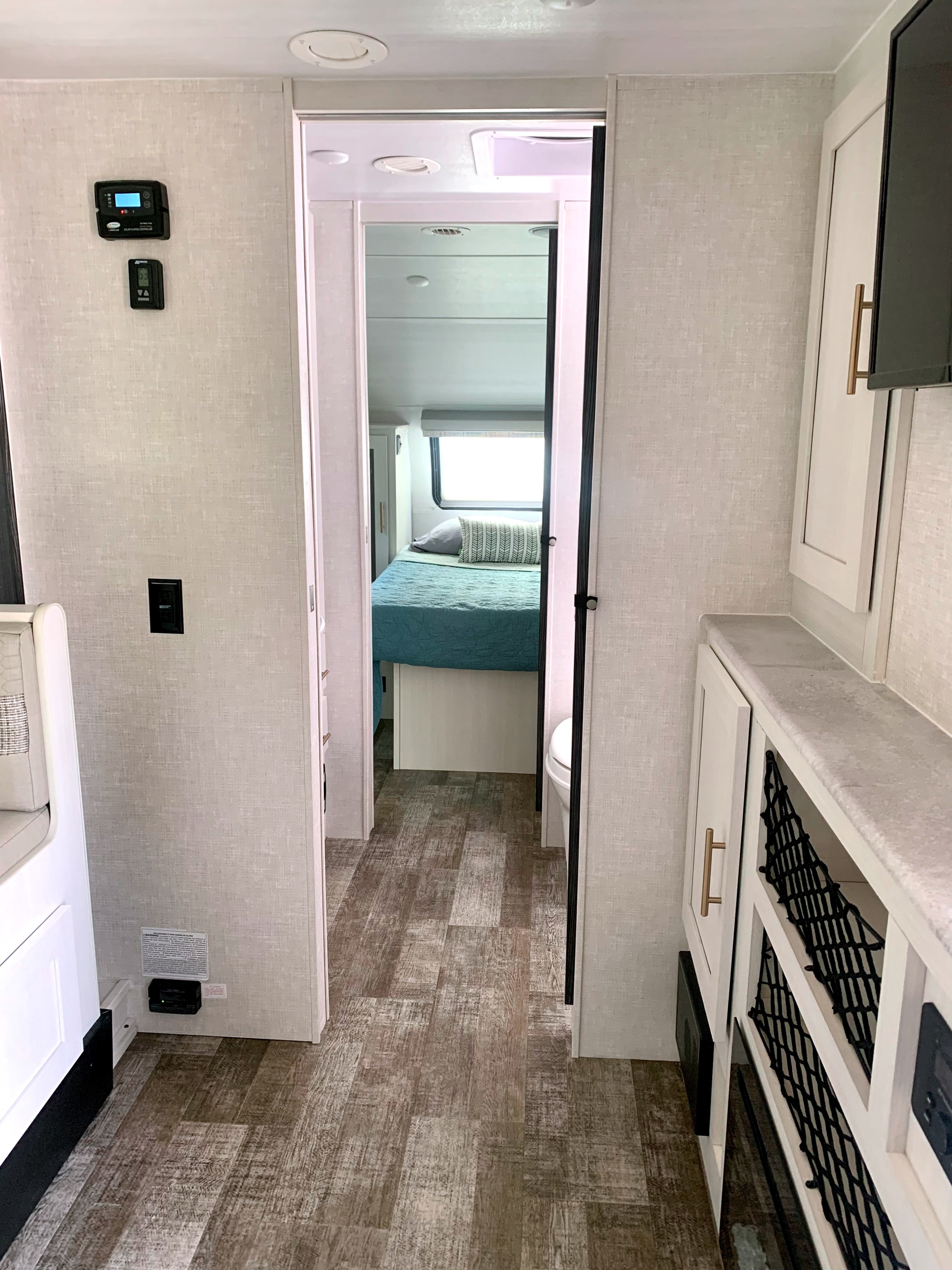 RV rental interior: a clean hallway leads to a cozy bedroom, featuring wall controls and smart storage solutions.. Forest River R-Pod 202 2021