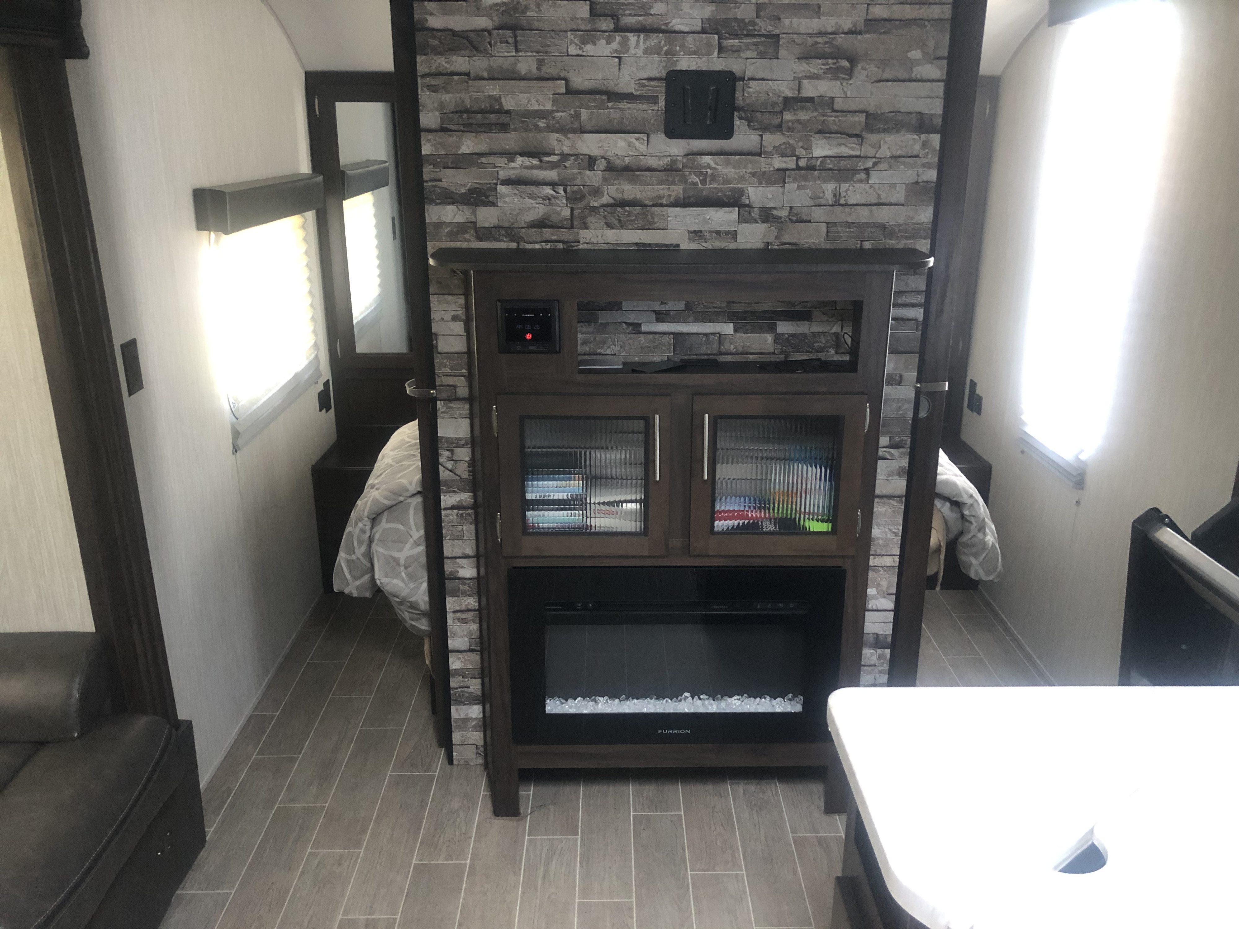 Modern RV rental interior: entertainment unit with fireplace, cozy bedroom, and living area.. Forest River Cherokee Grey Wolf 2020