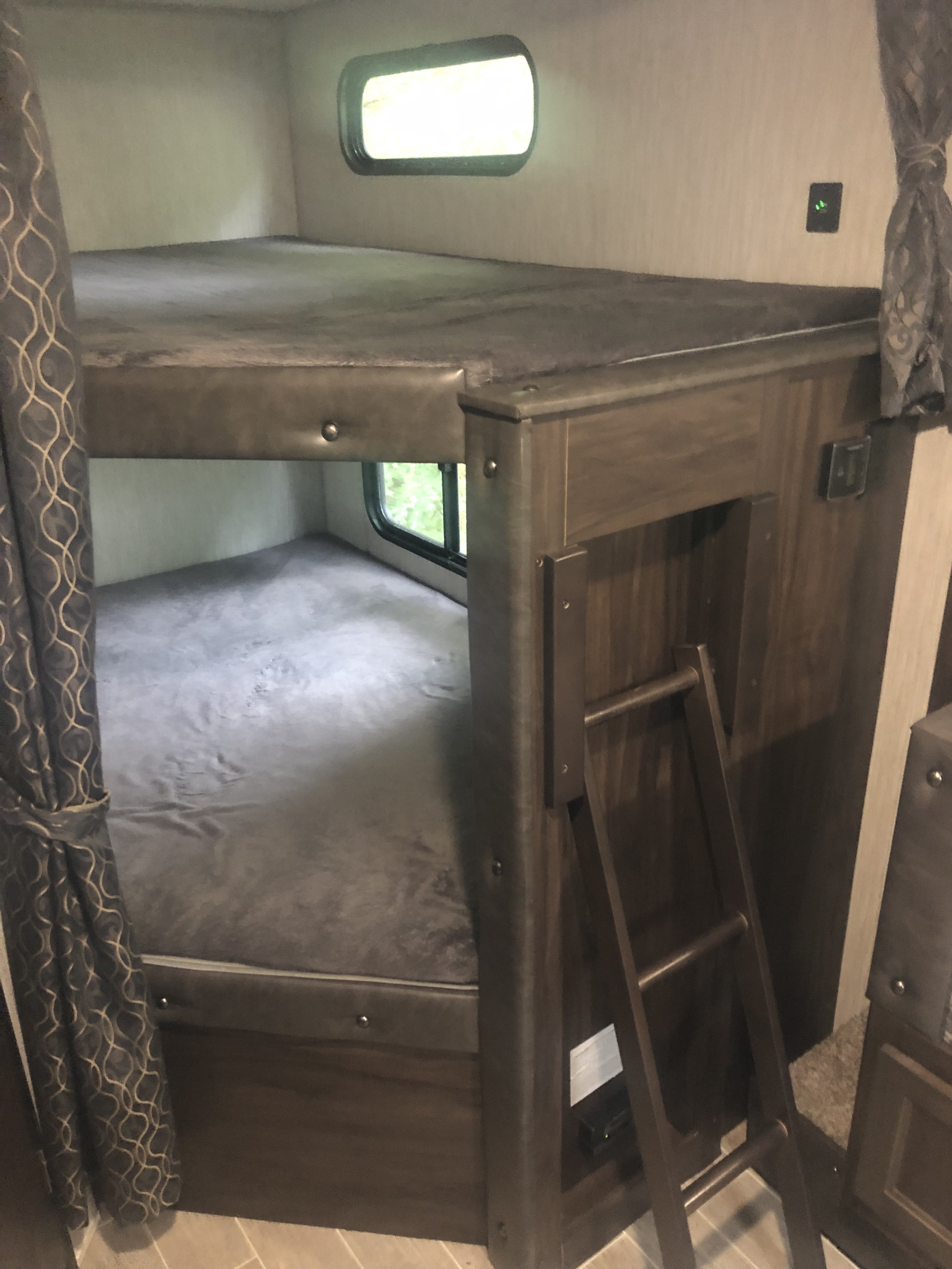RV rental bunk beds: a cozy interior view with upper and lower bunks, an access ladder, and window.. Forest River Cherokee Grey Wolf 2020