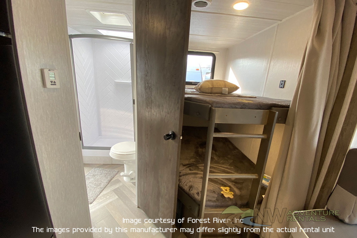 RV rental interior featuring a compact bathroom with shower/toilet on the left and bunk beds on the right.. Forest River X-Lite 2021