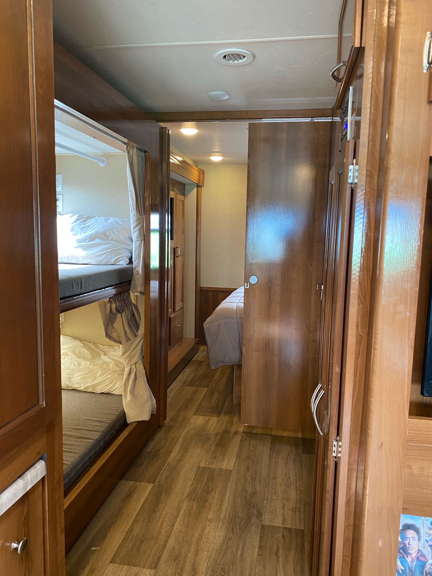 This inviting RV rental interior showcases a hallway with bunk beds on the left and warm wood finishes throughout, leading to a bedroom.. Coachmen Pursuit, bunk beds, low mileage, saves gasoline 2019