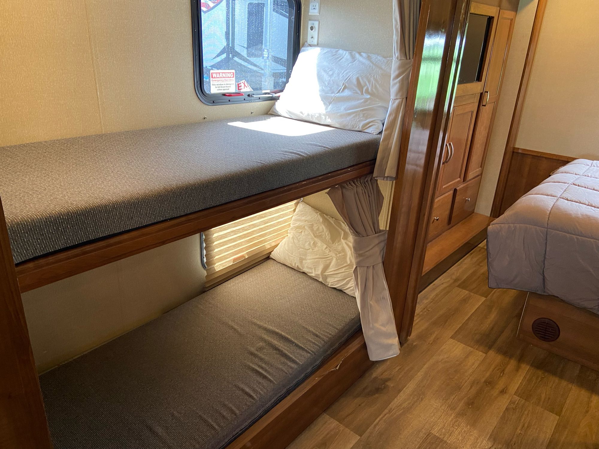 RV rental bunk beds: a compact sleeping area with pillows, privacy curtains, and an emergency exit window.. Coachmen Pursuit, bunk beds, low mileage, saves gasoline 2019