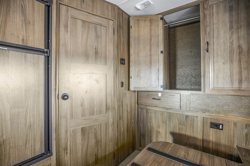 Compact RV rental interior with wood paneling, featuring a fridge, open wardrobe, and door. Perfect for travelers.. Mercedes-Benz Prism 2017