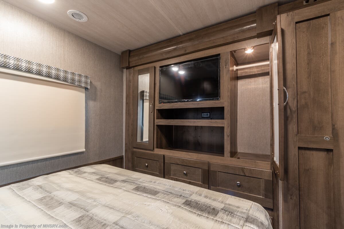 Inside an RV rental bedroom featuring a TV, built-in storage, closet, and a cozy bed setup.. Nexus Rebel 2022