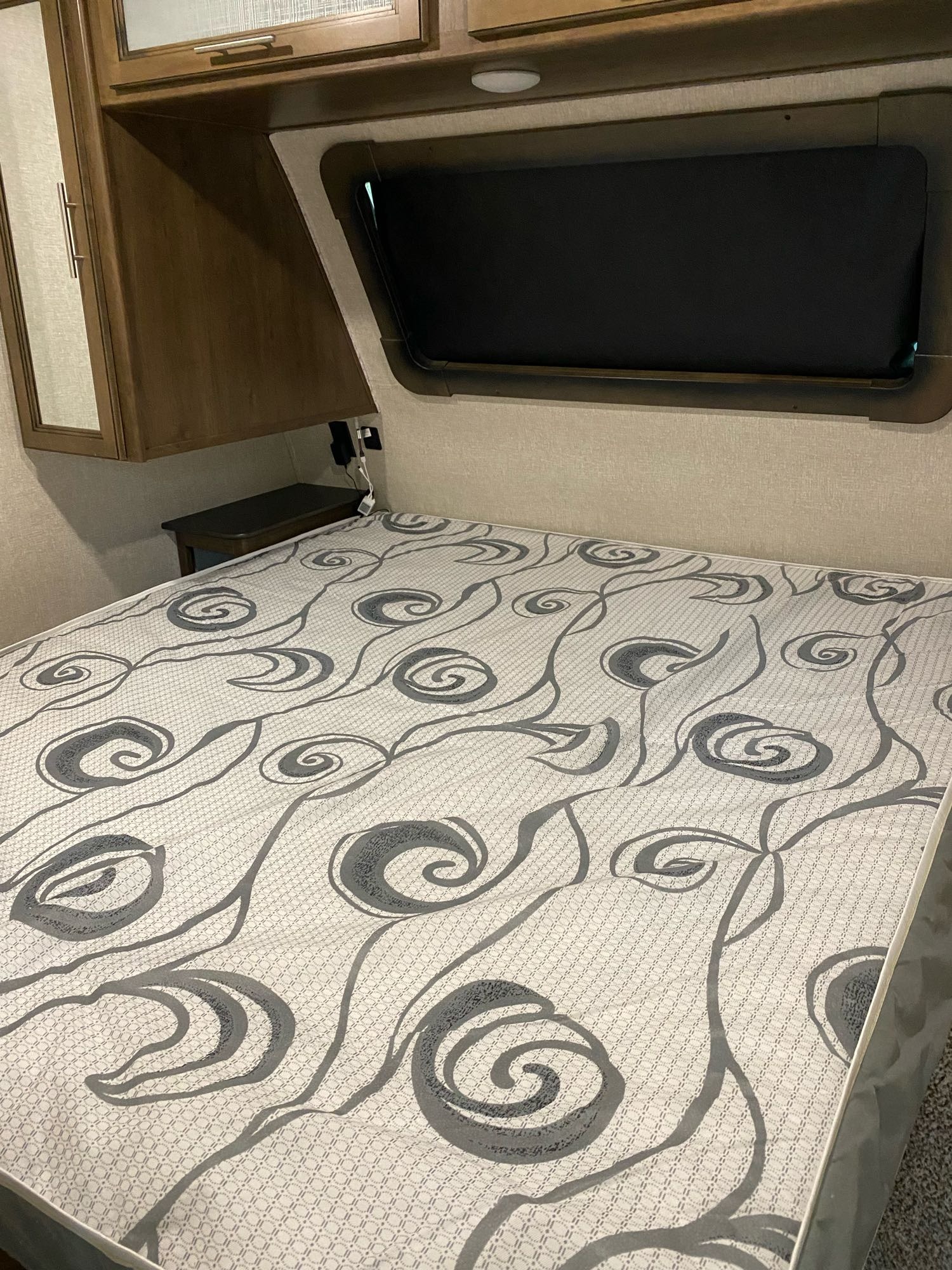 RV rental bedroom: Features a patterned mattress, overhead storage, and shaded window for a restful night.. Keystone Cougar Half-Ton 2020