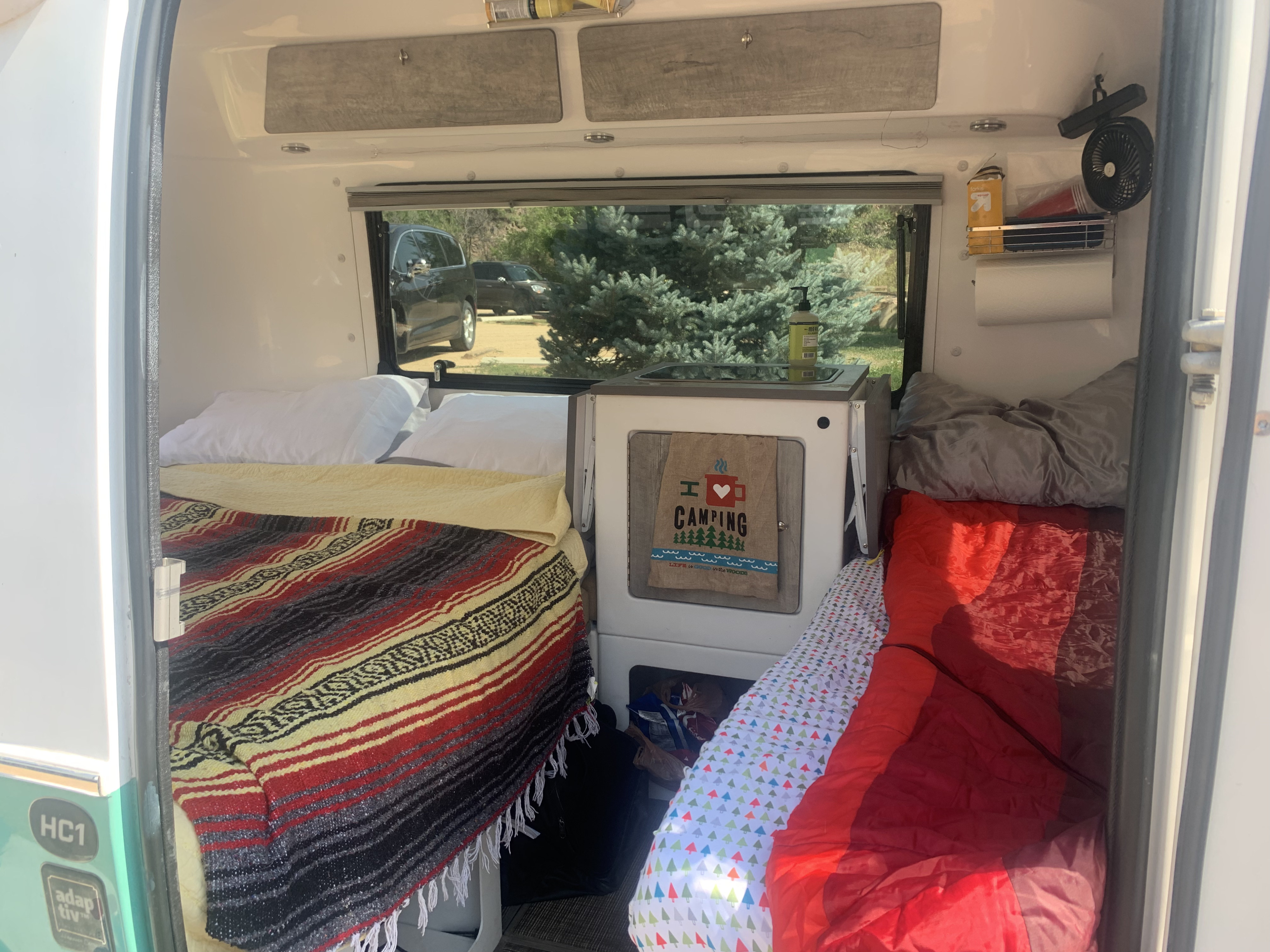 Compact RV rental camper interior: beds, mini-kitchen, and storage for a cozy camping adventure.. Happier Camper HC1 2020