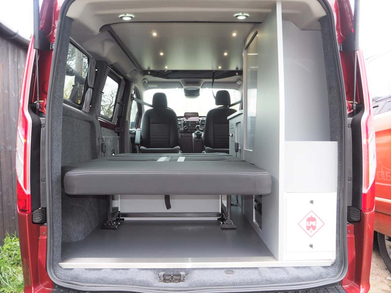 Ready for adventure! This rv rental campervan interior features a pull-out bed, storage, and front cabin views.. Ford Transit Custom 2+2 berth Pop Top, Manual 2022
