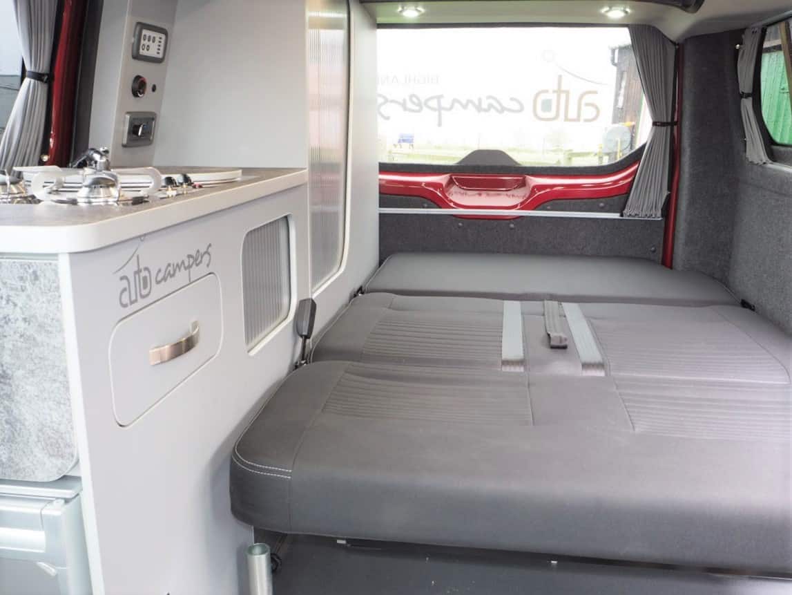 Explore this RV rental's versatile interior: a compact kitchenette on the left, and a comfy convertible bed/seating area on the right.. Ford Transit Custom 2+2 berth Pop Top, Manual 2022