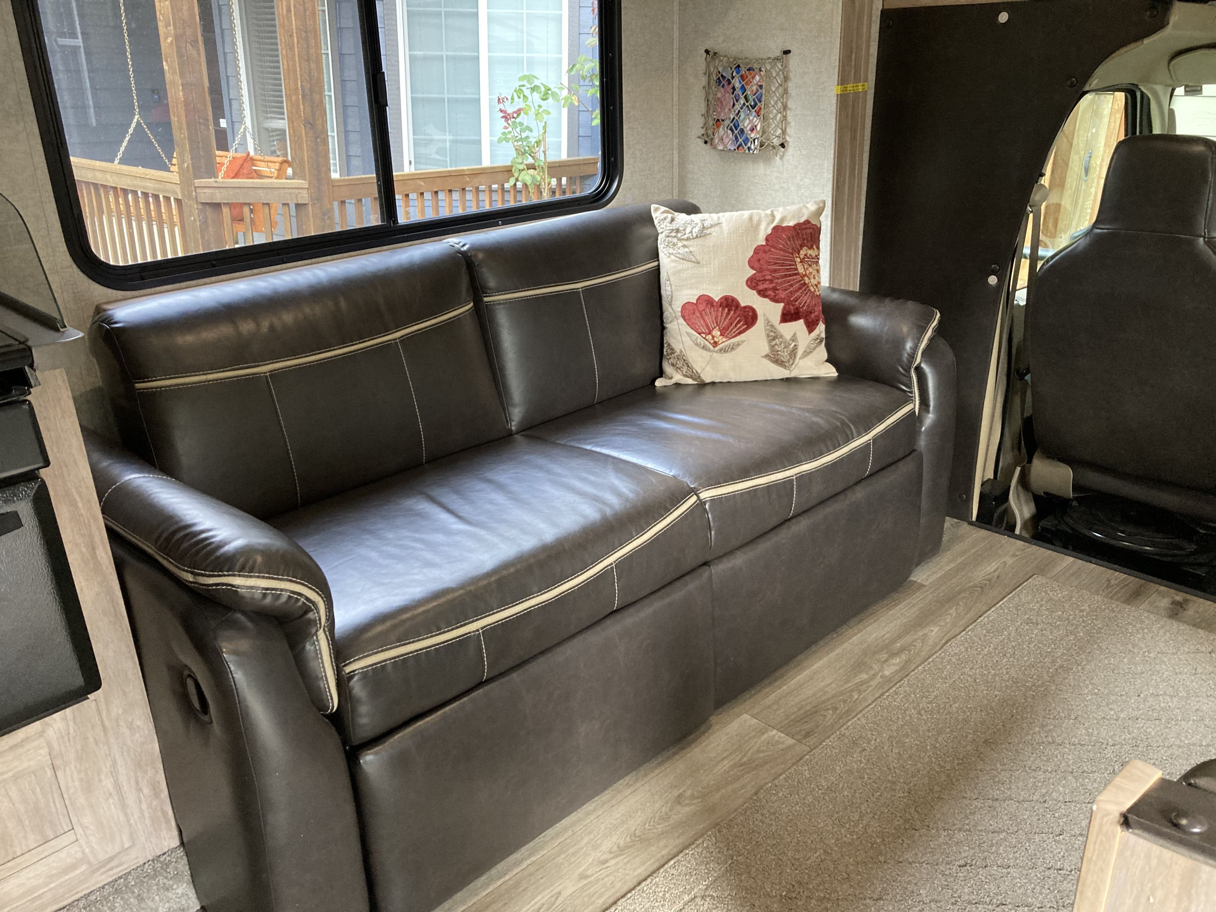Cozy RV rental living space featuring a dark brown sofa, decorative pillow, and outdoor view. Ideal for comfortable travel.. Forest River Other 2017
