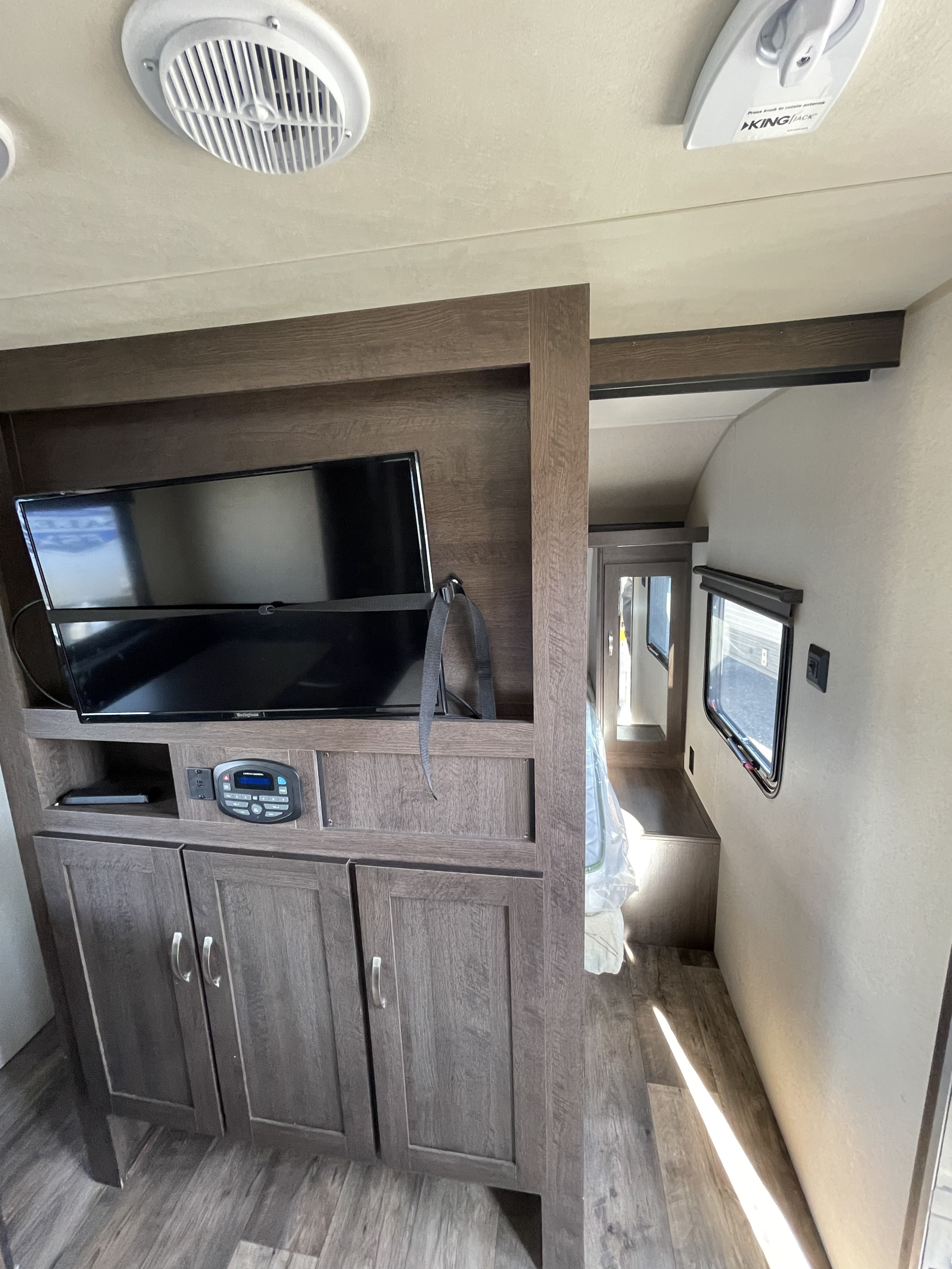 Spacious RV rental interior features an entertainment center with TV, stereo, storage, and a bright bedroom.. Forest River Cruise Lite 2019