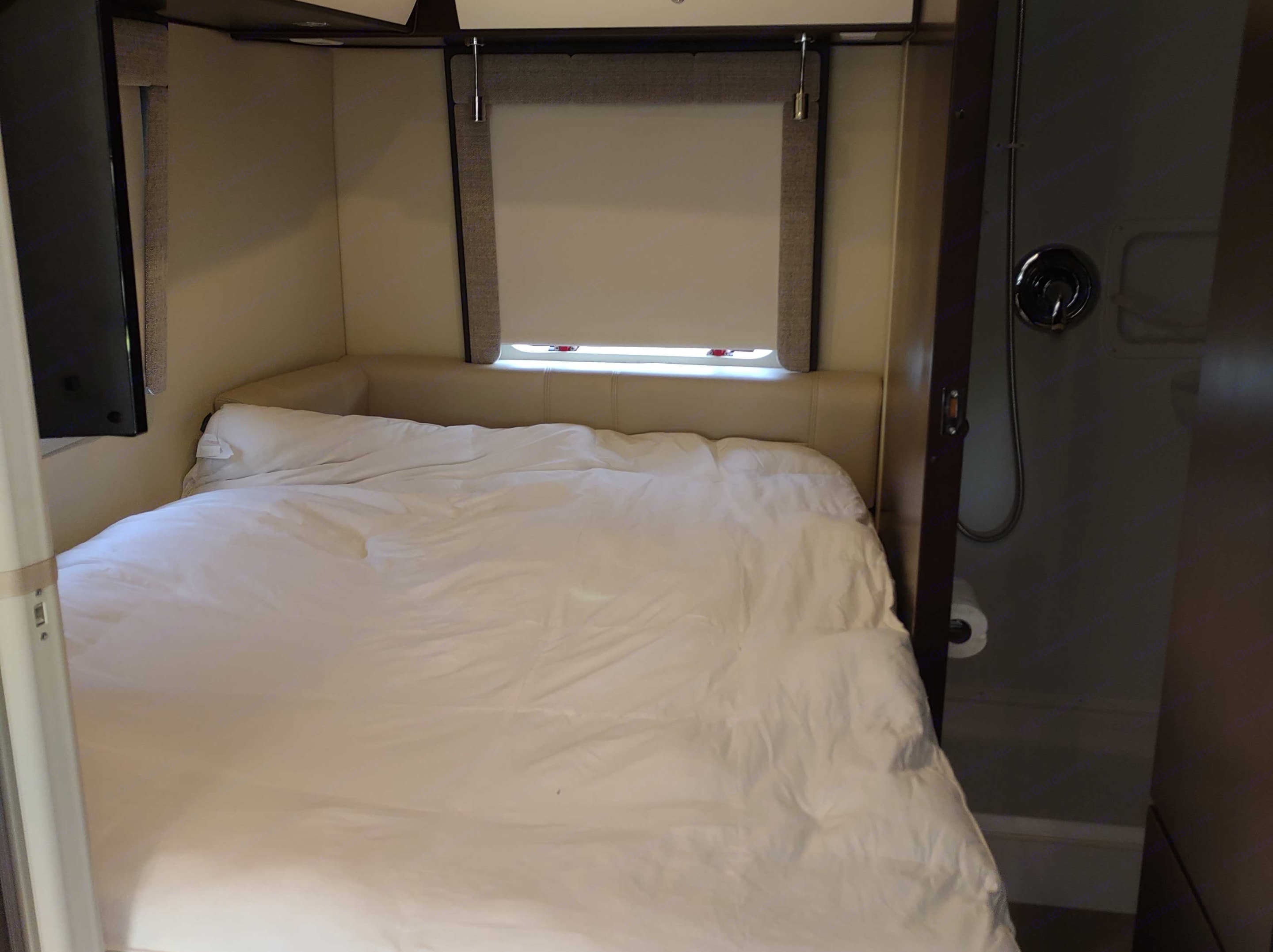 Comfortable RV rental bedroom with white bedding, window, TV, and adjacent shower. Ideal for your next trip!. Leisure Travel Serenity 2016