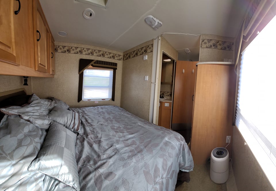 Comfortable RV rental bedroom interior with patterned bed, overhead cabinets, and compact layout.. Jayco Greyhawk 2007