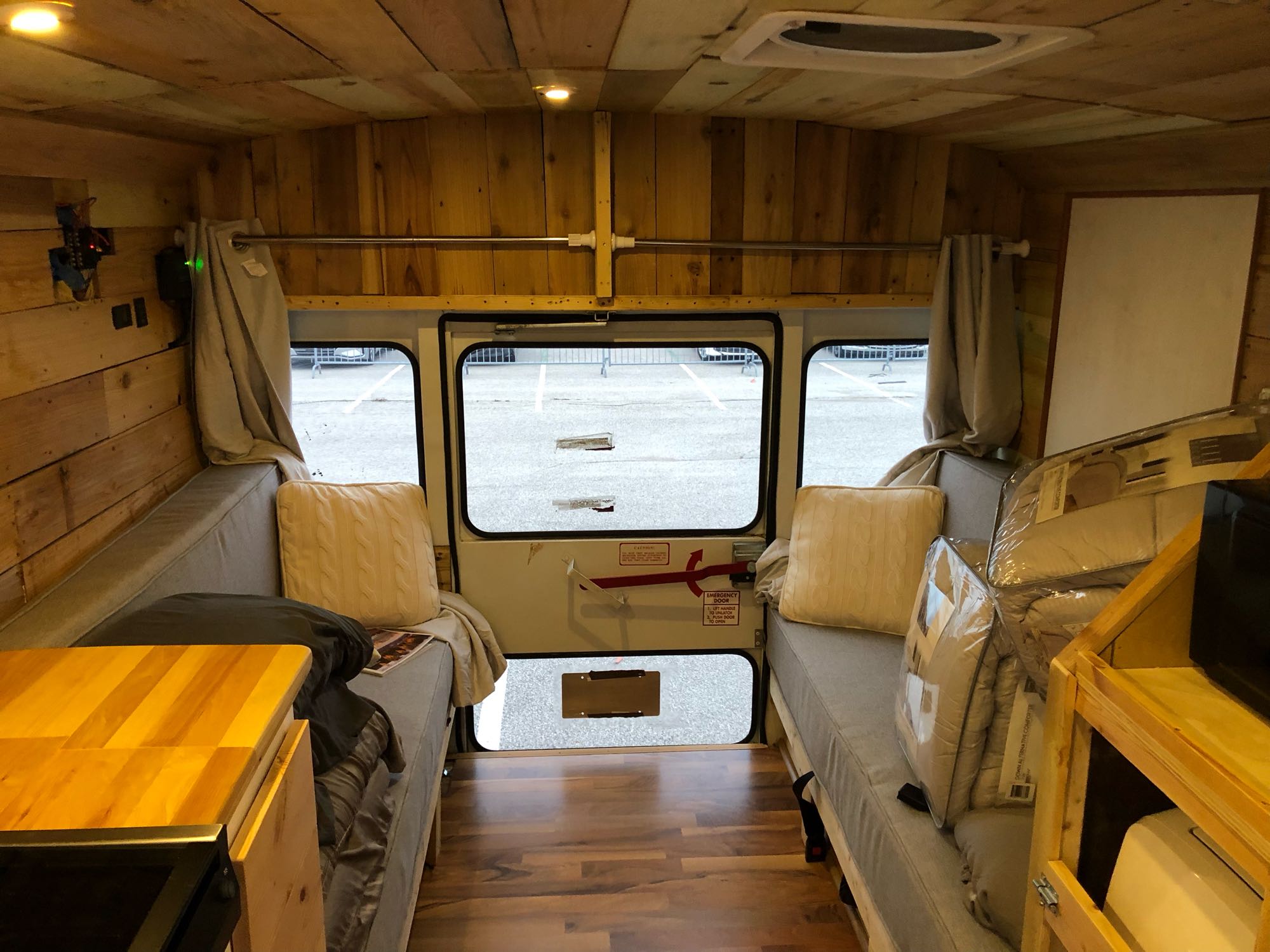 RV rental interior: A cozy, wood-paneled bus/van conversion with facing beds and a rear view, perfect for travel.. Chevy Express 3500 Mini Bus 2002