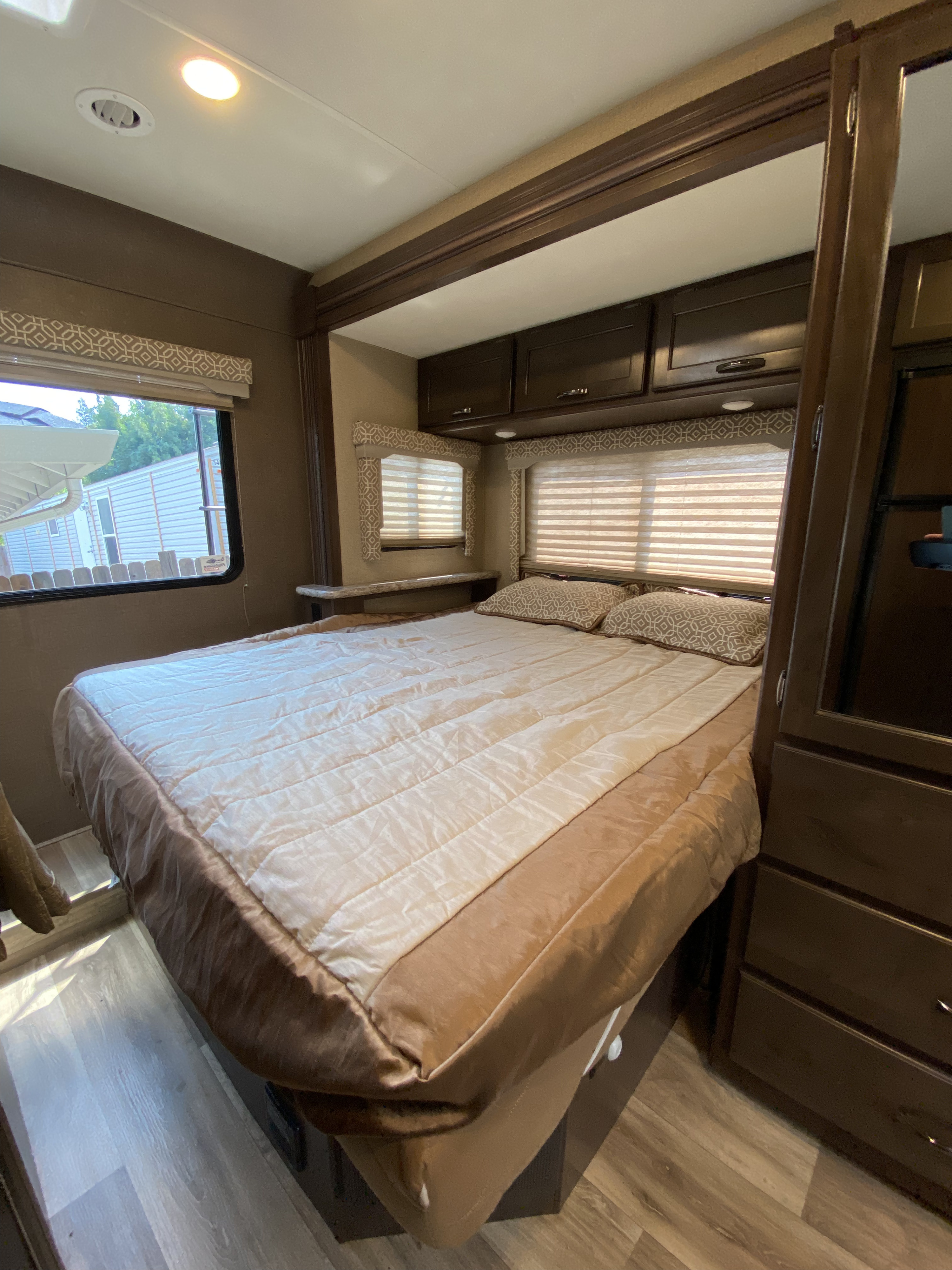 Explore this comfy RV rental bedroom! Features include a large bed, ample overhead storage, and windows with blinds.. Thor Motor Coach Freedom Elite 2019