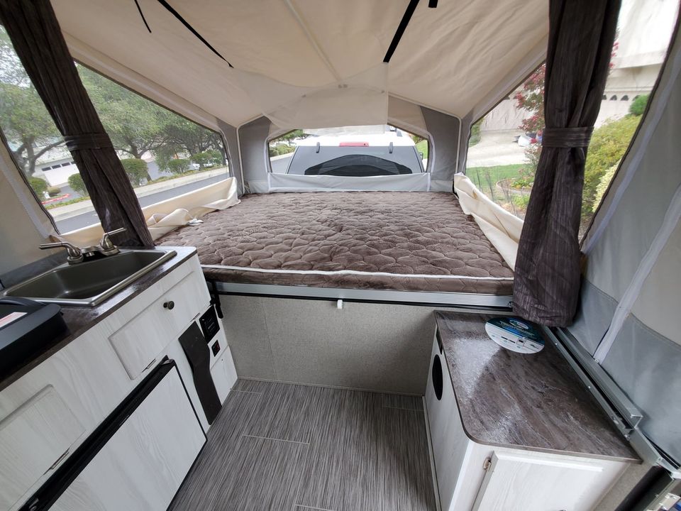 RV rental ready for adventure! This pop-up camper's interior has a comfy bed, sink, and bright window views.. Forest River Rockwood ESP 2019