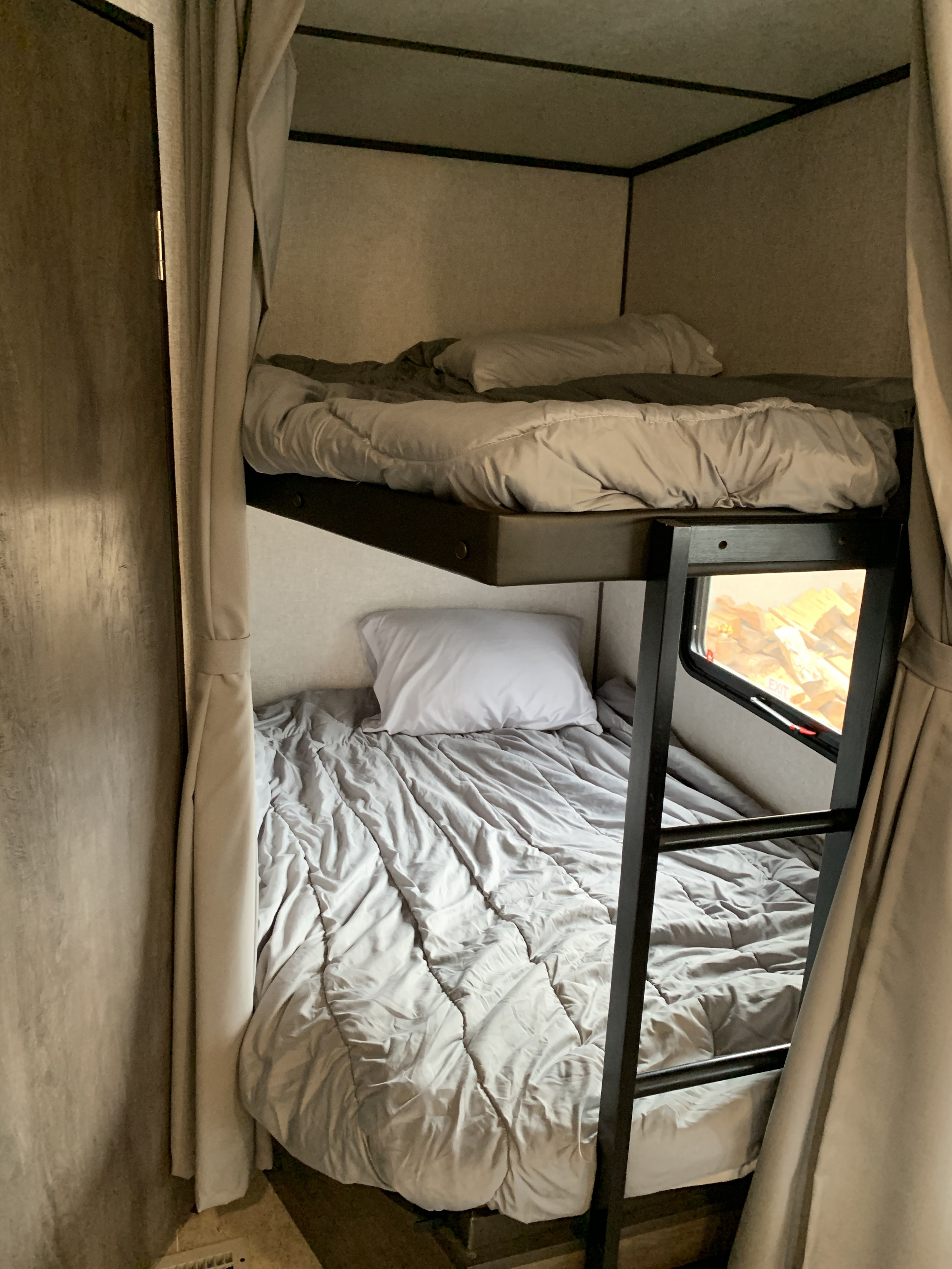 Cozy bunk beds in an RV rental, with soft bedding and a ladder. Perfect for compact, comfortable travel.. Dutchmen Coleman 2021