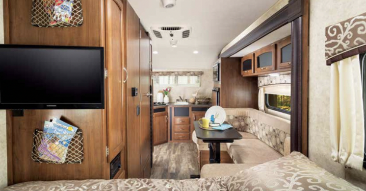 Spacious RV rental interior featuring a TV, comfy U-shaped dinette, and functional kitchen. Your mobile home awaits!. Jayco Hummingbird 2017