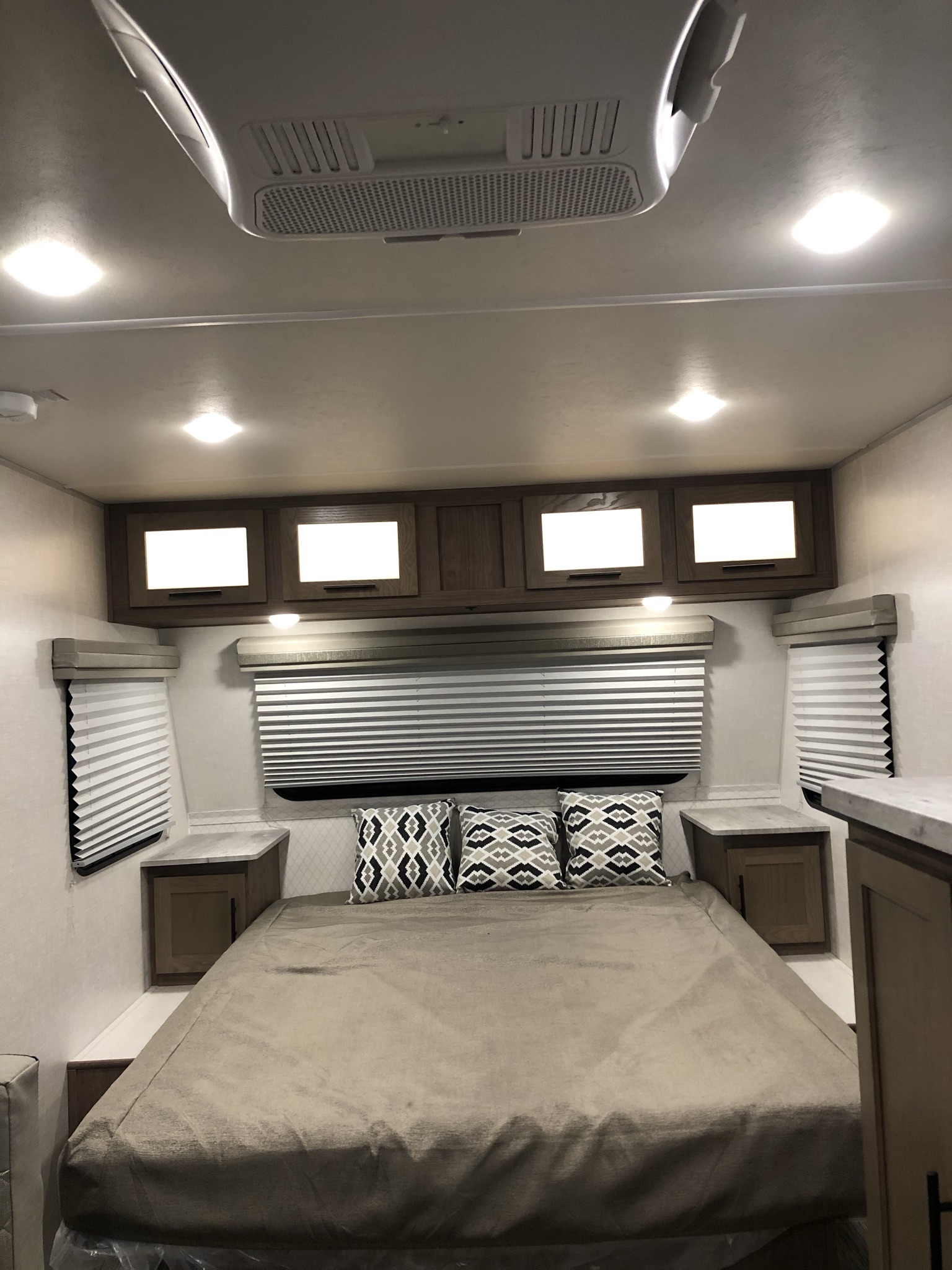 This inviting RV rental bedroom features a bed, integrated storage, window blinds, and bright overhead lighting.. Forest River R-Pod 2020