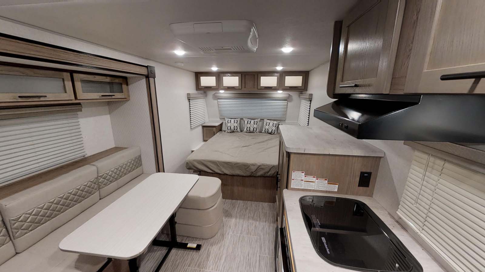 This RV rental shows a wide-angle view of its interior with a bed, dinette, and kitchen area.. Forest River R-Pod 2020
