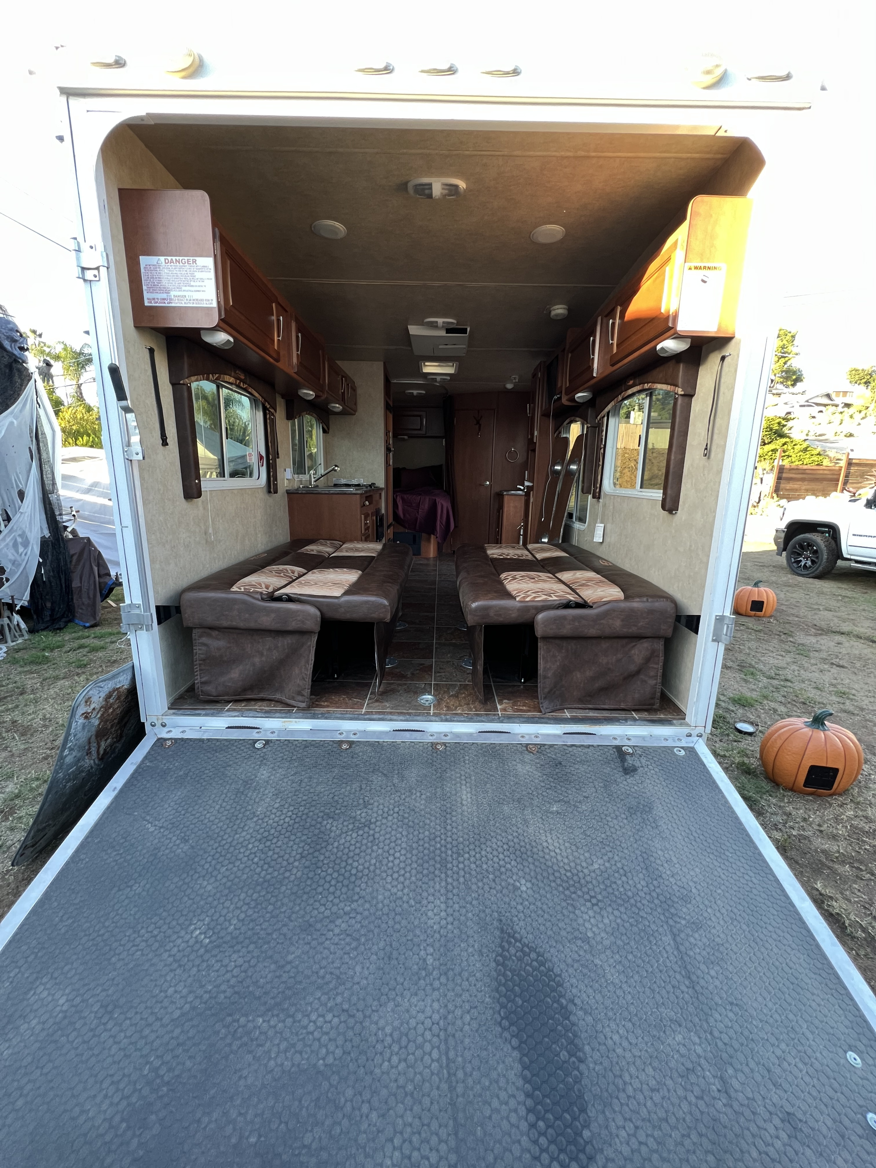 Spacious RV rental toy hauler interior with ramp down, showing seating, kitchen, and living space. Ideal for mobile adventures.. Forest River Stealth 2012