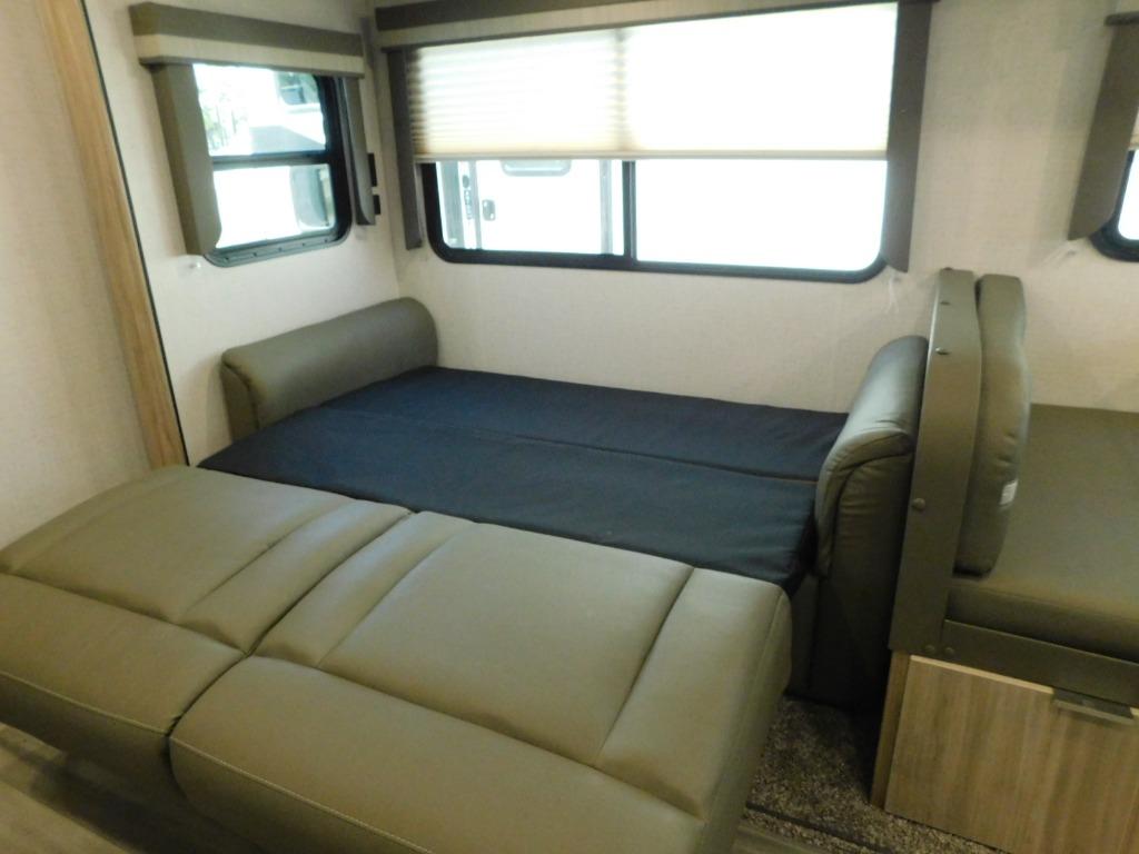 This RV rental interior offers a versatile living space with a convertible sofa bed/dinette and windows, ideal for travel comfort.. Winnebago Minnie 2021
