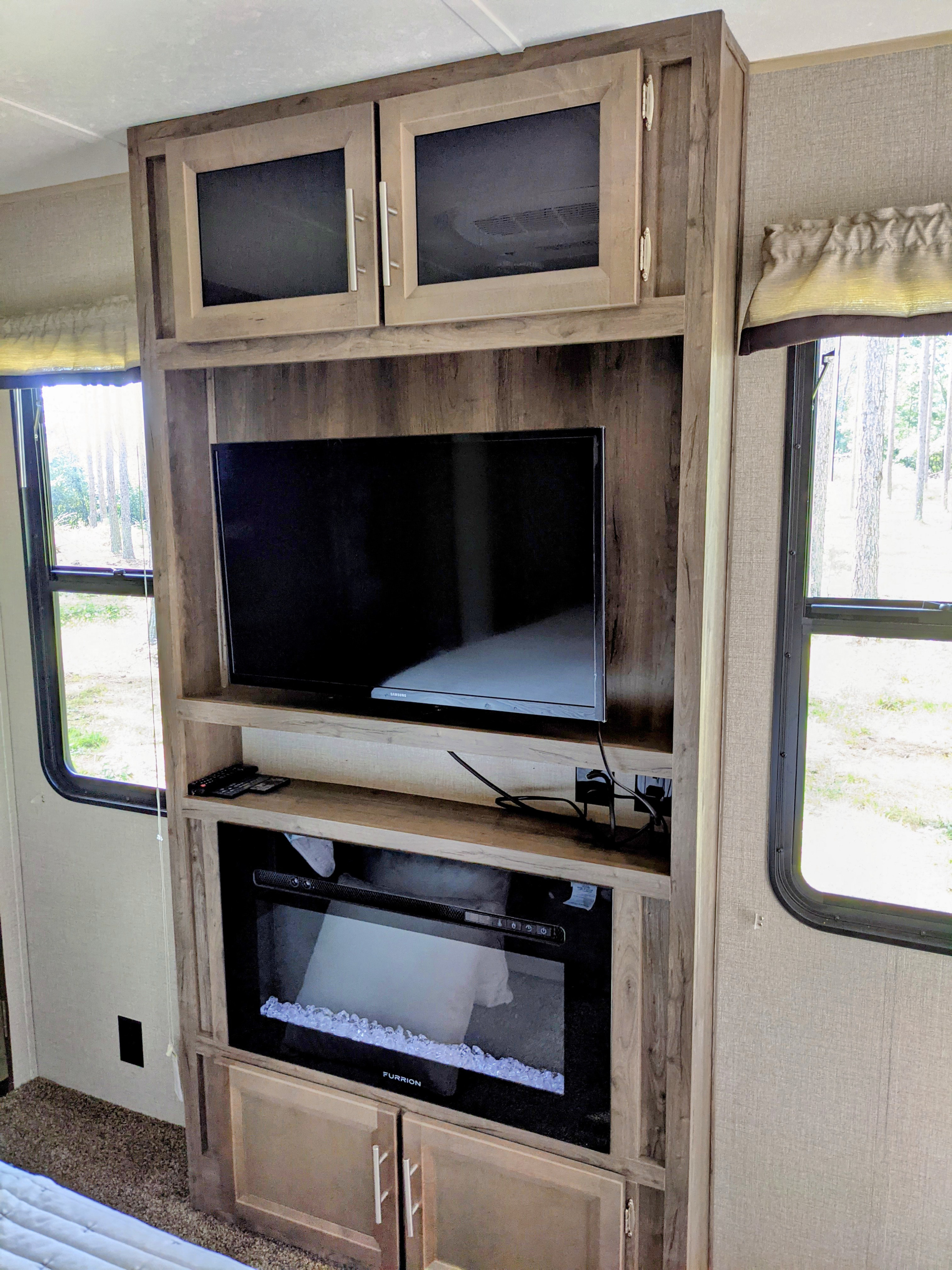 RV rental interior: Built-in entertainment system with Samsung TV, Furrion electric fireplace, and storage cabinets, creating a cozy living space.. Forest River euroa 2021