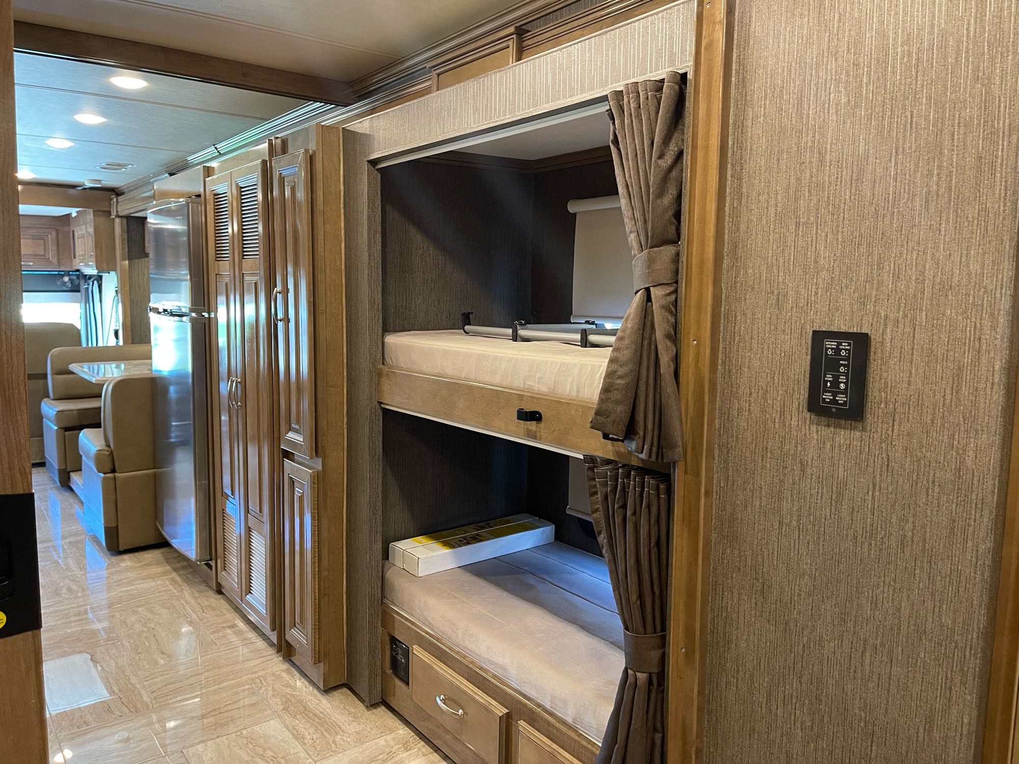 Modern RV rental interior showcasing comfy bunk beds with privacy curtains, a full kitchen, and dinette area.. Thor Motor Coach Aurora 2020