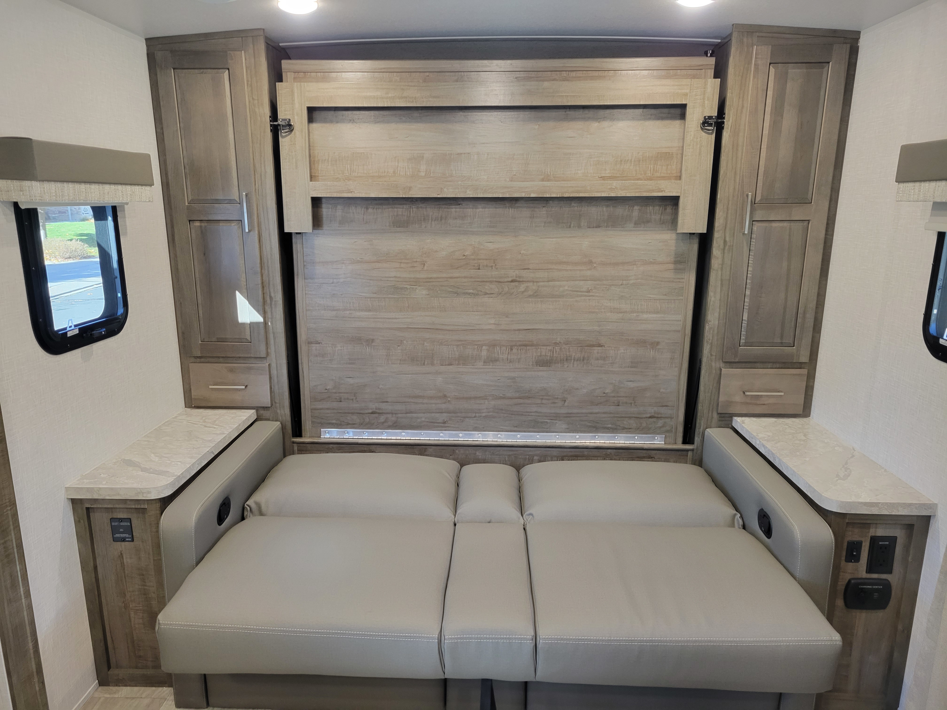 RV rental interior featuring a convertible sofa that transforms into a bed, flanked by storage cabinets and charging outlets.. Forest River Flagstaff Micro Lite 2022