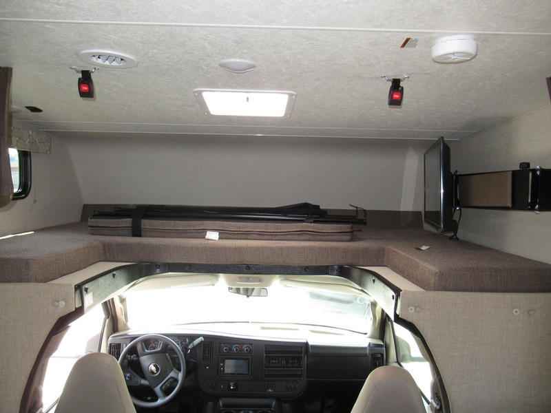 This RV rental interior features a spacious cab-over bunk bed, TV, and front cockpit view, ideal for travel.. Coachmen Freelander 2019