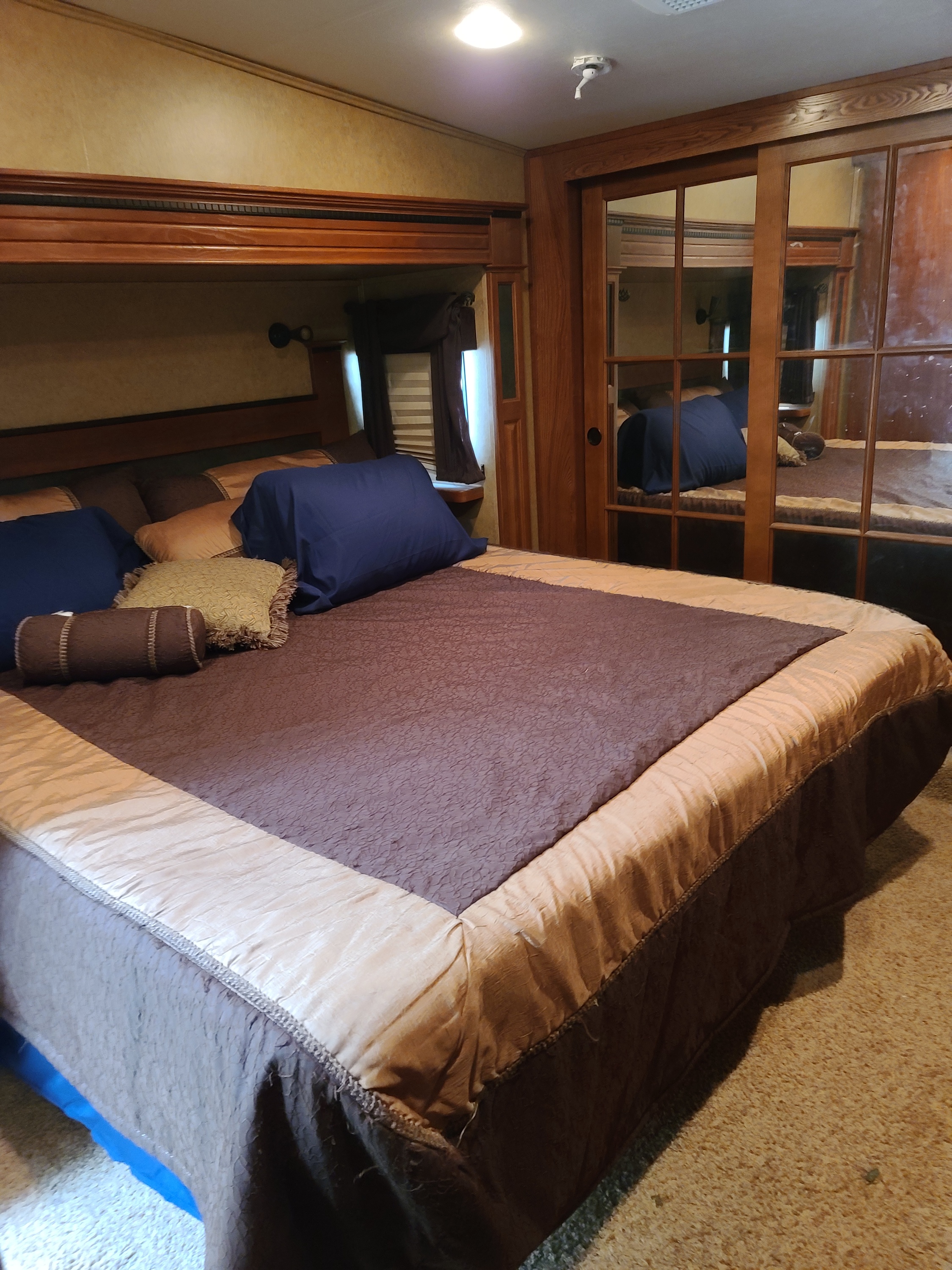 Step inside this RV rental's cozy bedroom. Features a large bed with pillows, inviting bedding, and mirrored closet doors.. Komfort Komfort 2016