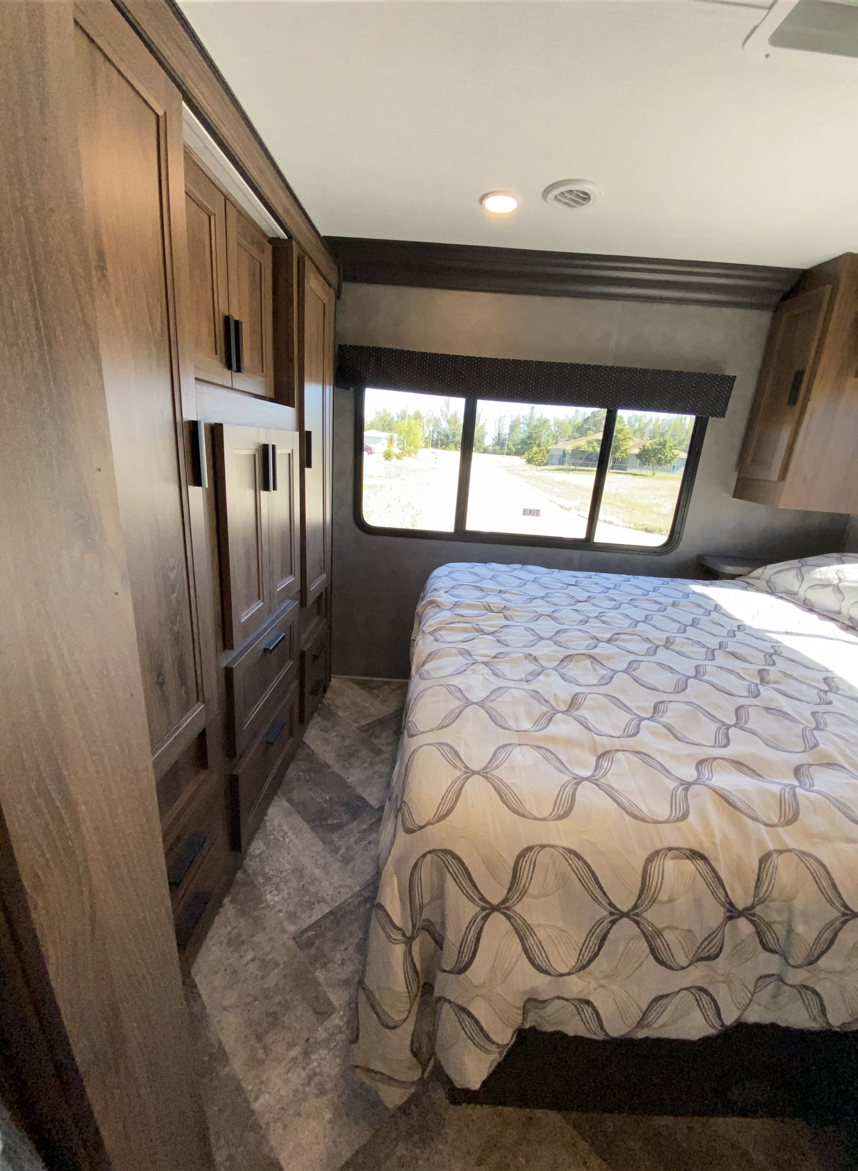 RV rental's inviting bedroom features built-in storage, a patterned bed, and large window with outdoor views.. Forest River Other 2021