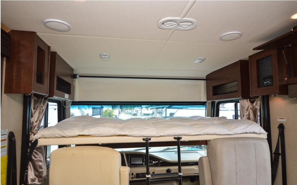 RV rental interior: cozy bunk bed over driver's cabin, with overhead storage, dashboard, and outside view.. Fleetwood Other 2017