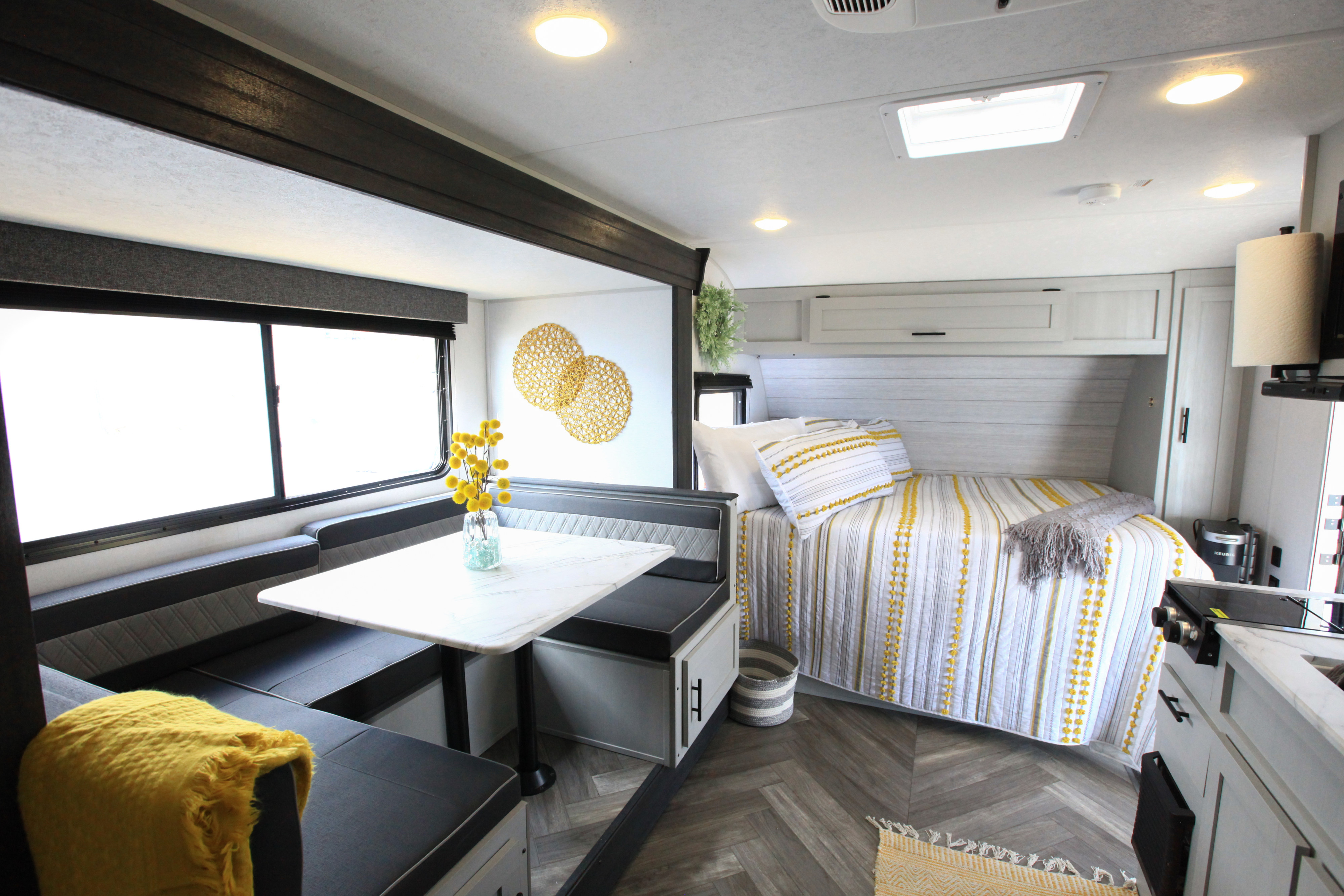 Modern RV rental interior: Features a cozy bed, dining area, and compact kitchen with yellow accents.. Forest River Salem FSX platinum 2021