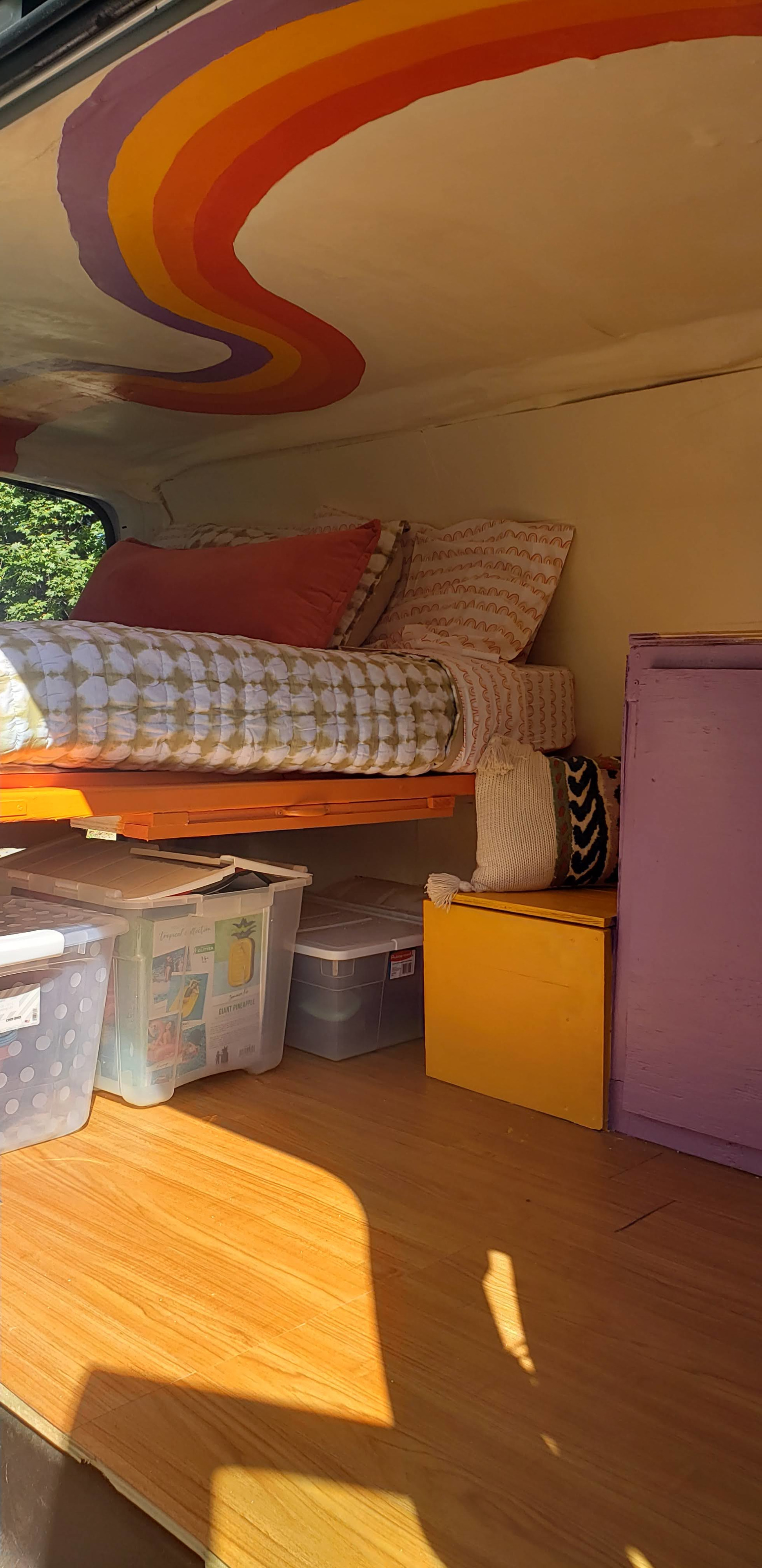 Colorful RV rental interior: bed, storage bins, unique rainbow ceiling, wood floor. Bright & ready for travel!. Chevrolet Express 2018
