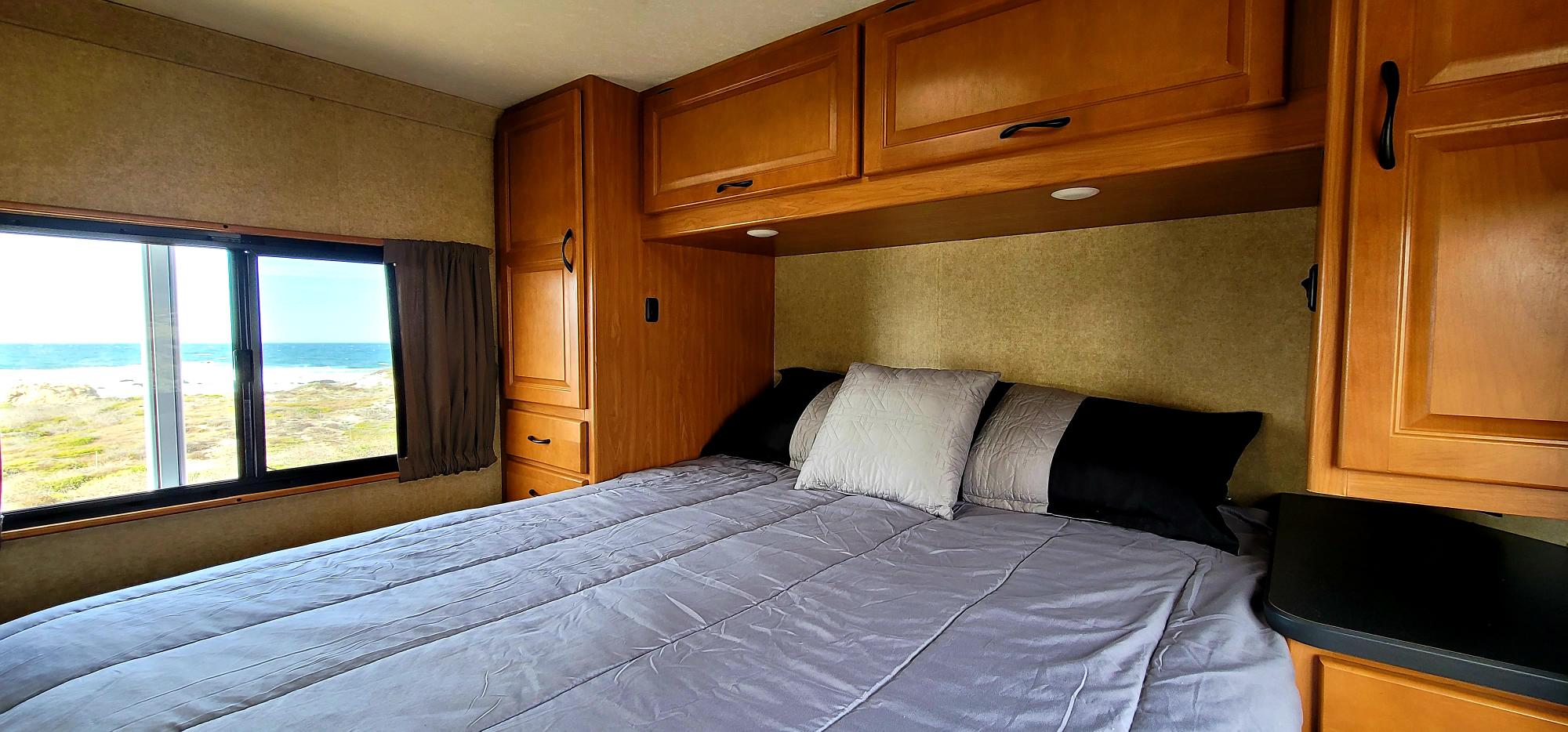 Scenic RV rental bedroom offering an ocean view, comfortable bed, and wooden cabinetry.. Thor Motor Coach Four Winds Majestic 2017