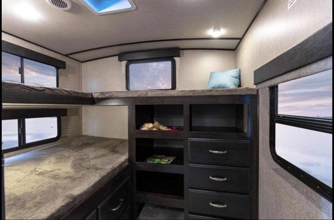RV rental interior featuring bunk beds with storage, windows, and skylight, perfect for family adventures.. Grand Design Imagine 2019