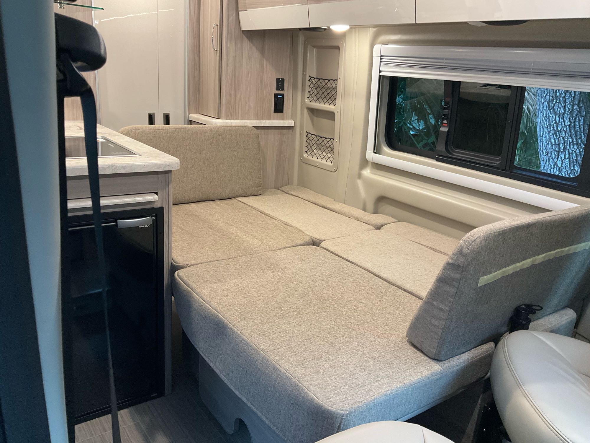 RV rental interior featuring a versatile bed/seating area, compact kitchenette, and window with outdoor views.. Thor Scope 2022