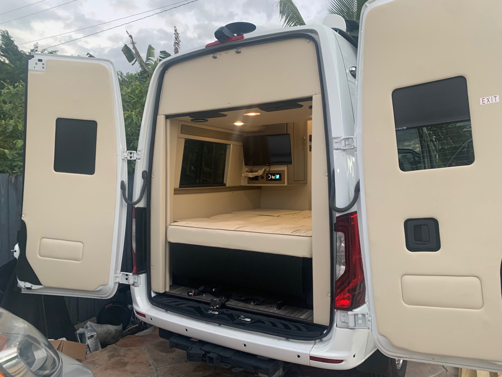 RV rental: Spacious camper van interior with bed, TV, and open rear doors, ready for adventure.. Midwest Automotive Designs Midwest Automotive Designs Class B 2021